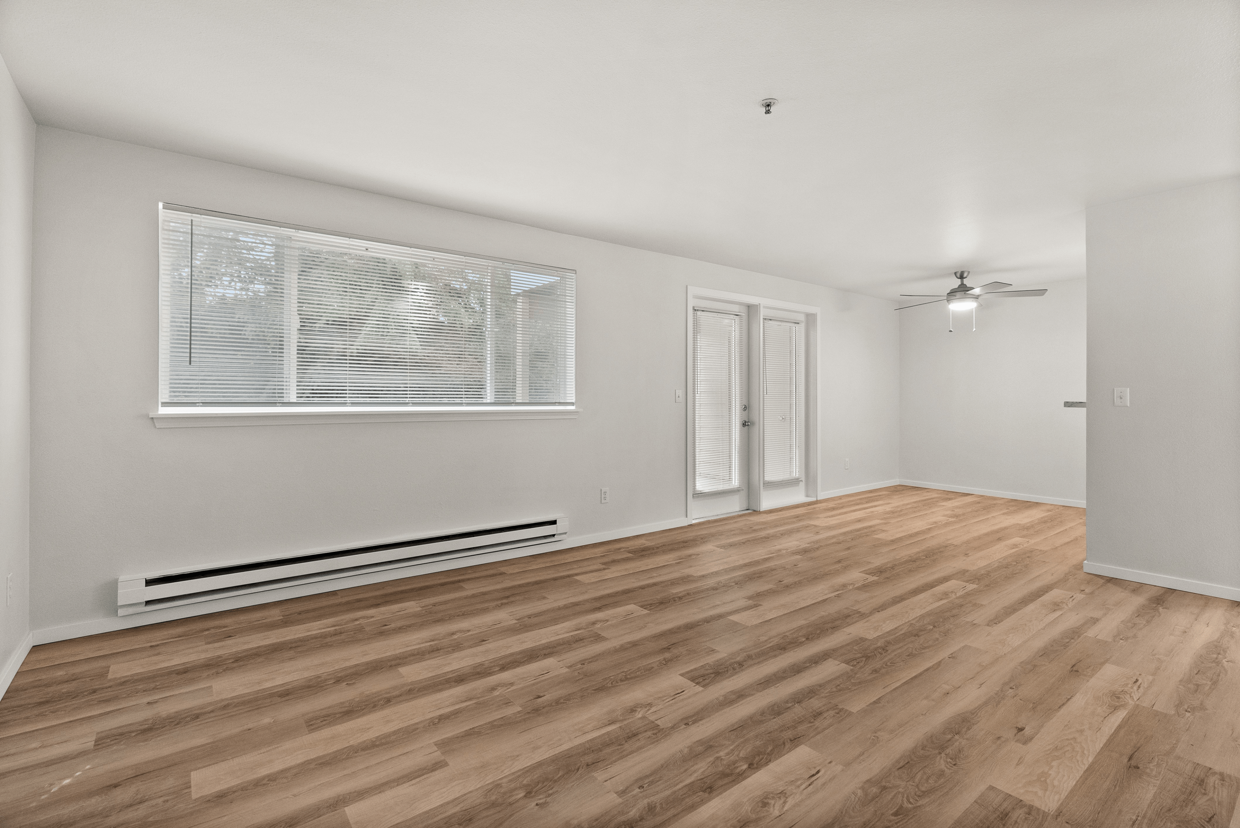 Bright, open-concept living space with elegant hardwood flooring, large windows, and modern ceiling fan.