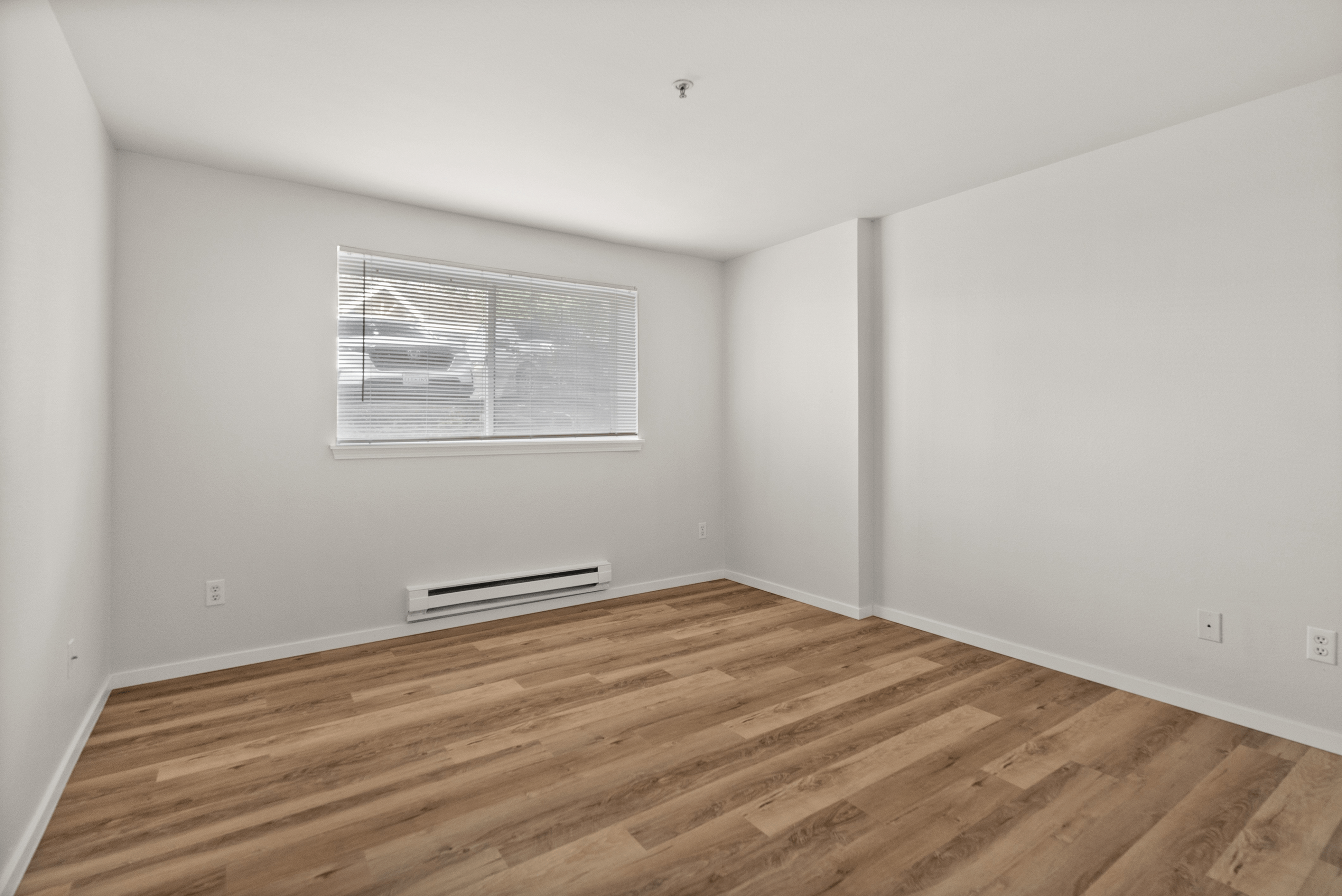 Bright, spacious room with modern wooden flooring and large window for natural light.