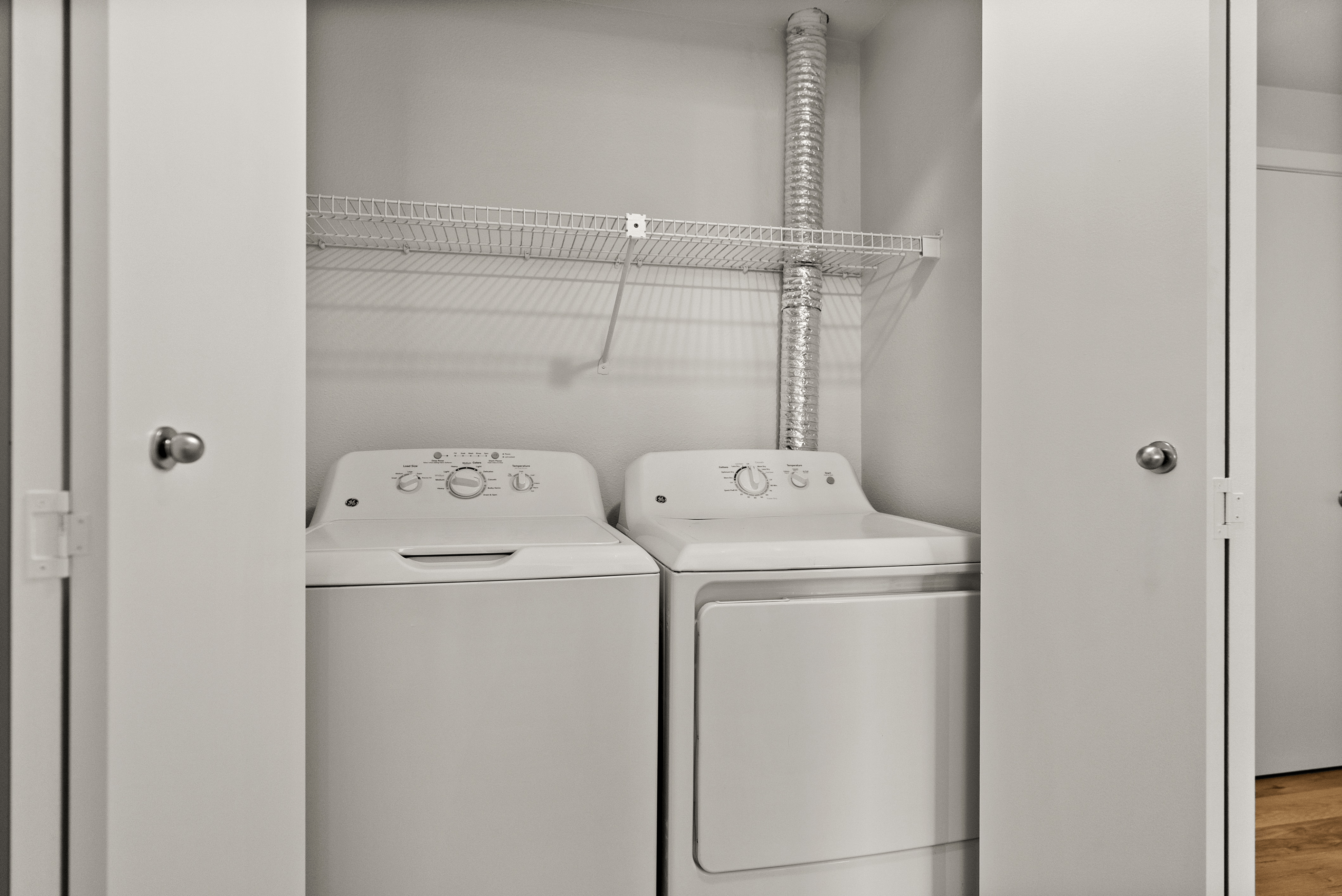 Modern apartment laundry area featuring sleek washer and dryer combination with spacious shelving.