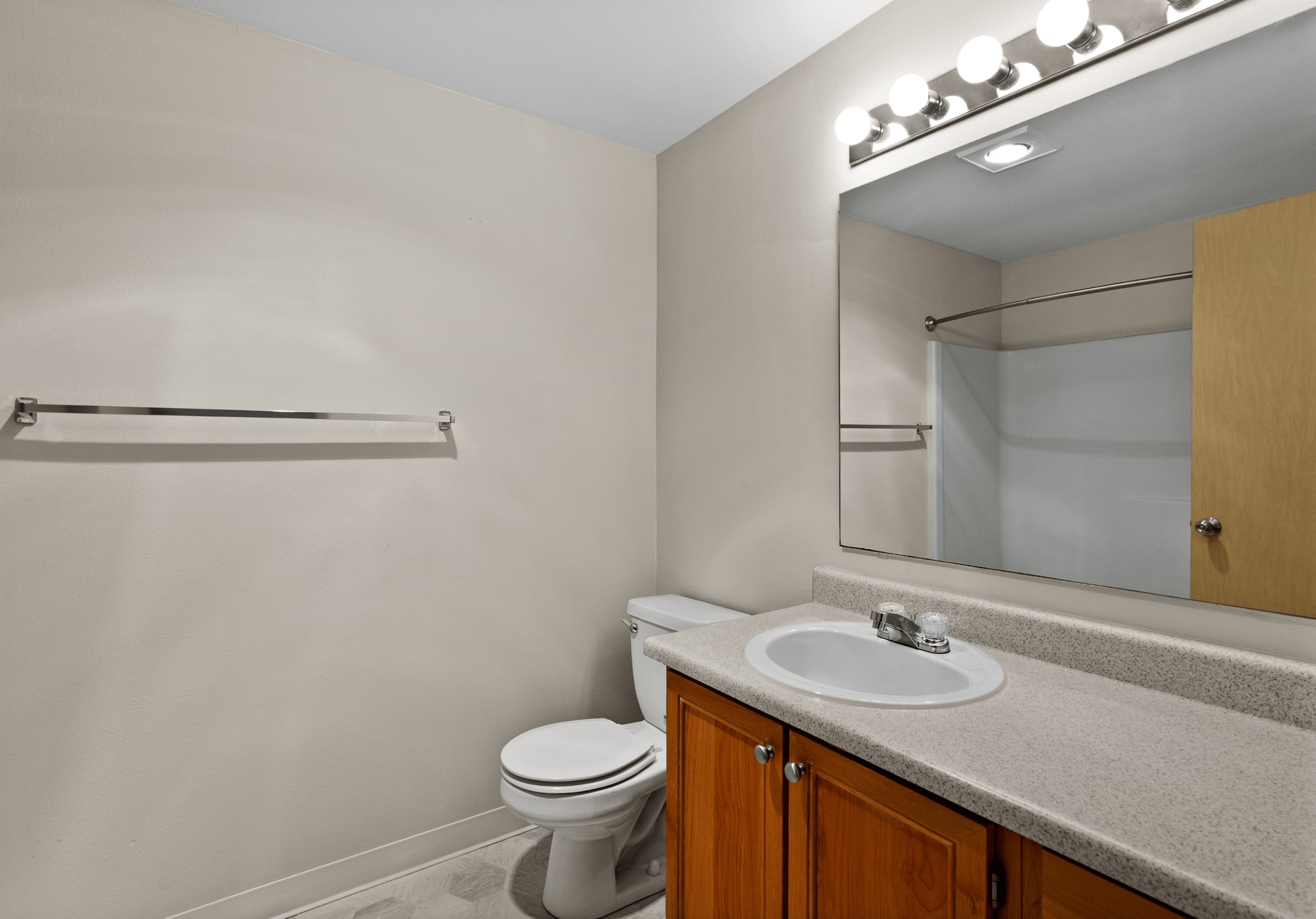 Modern bathroom featuring a large mirror, sleek countertop with sink, and wooden cabinetry for a minimalist design.