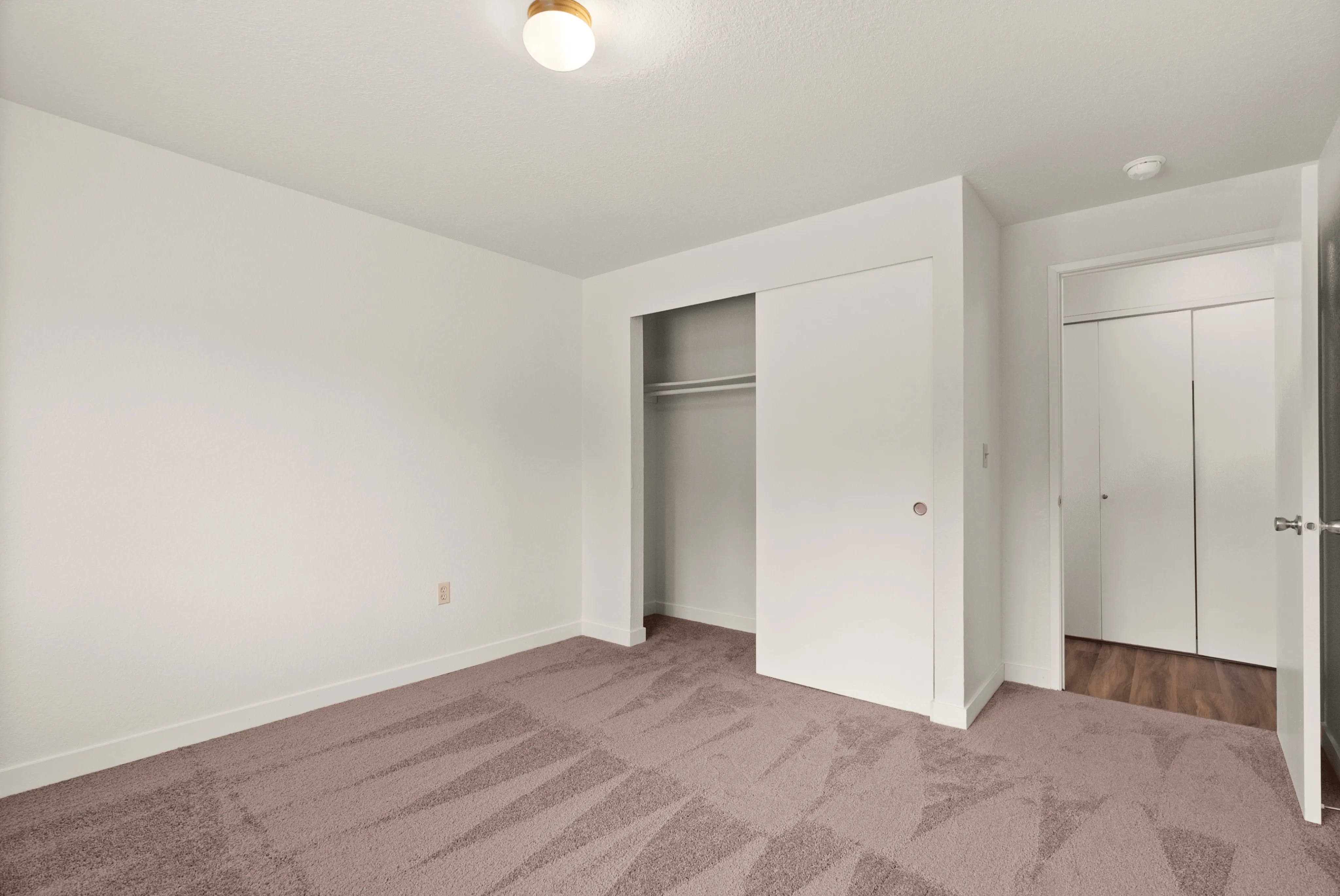Bright and inviting bedroom with plush carpet, built-in closet, and modern lighting.