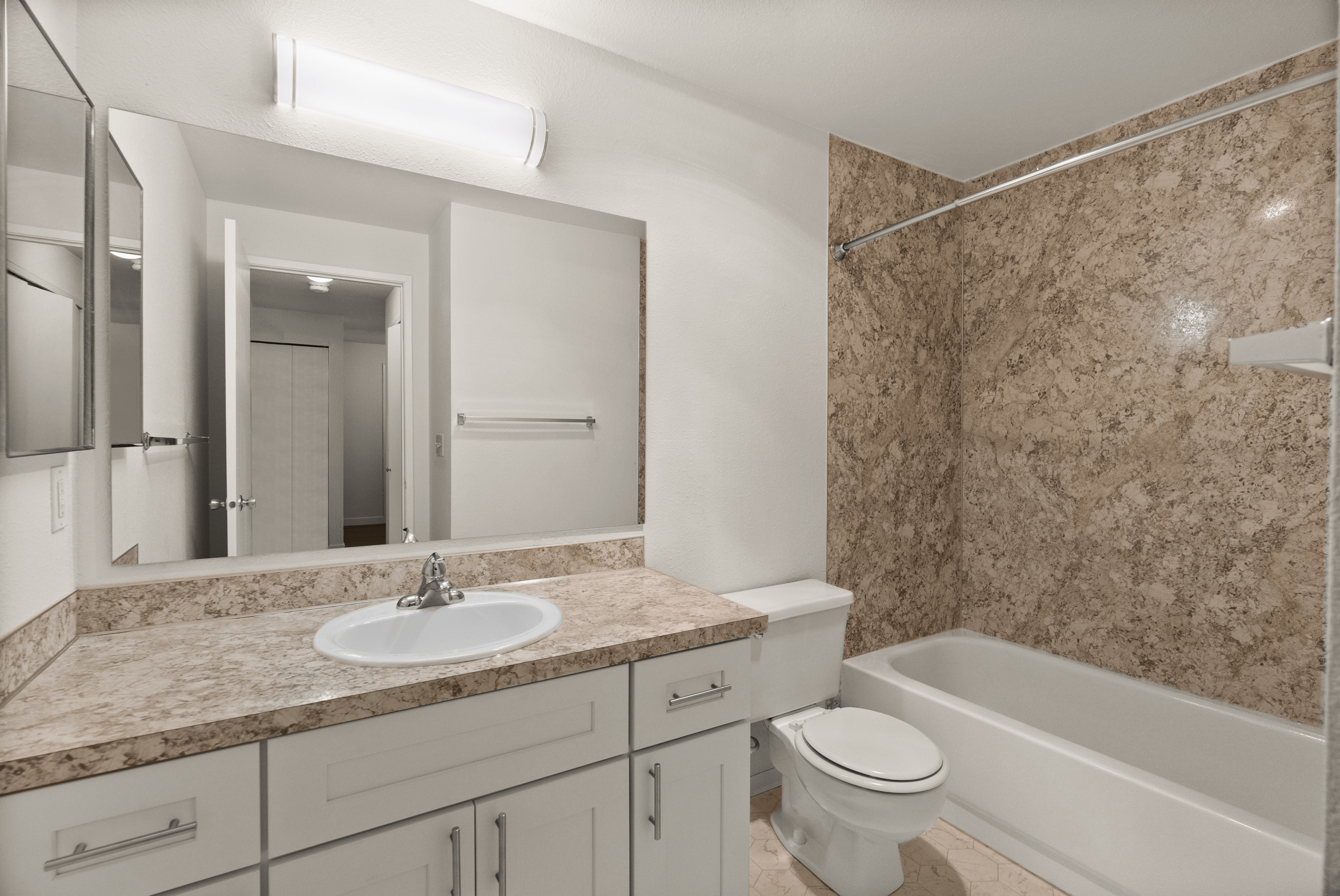 Modern bathroom with elegant marble walls, sleek vanity, and bright lighting, offering a luxurious and functional space.