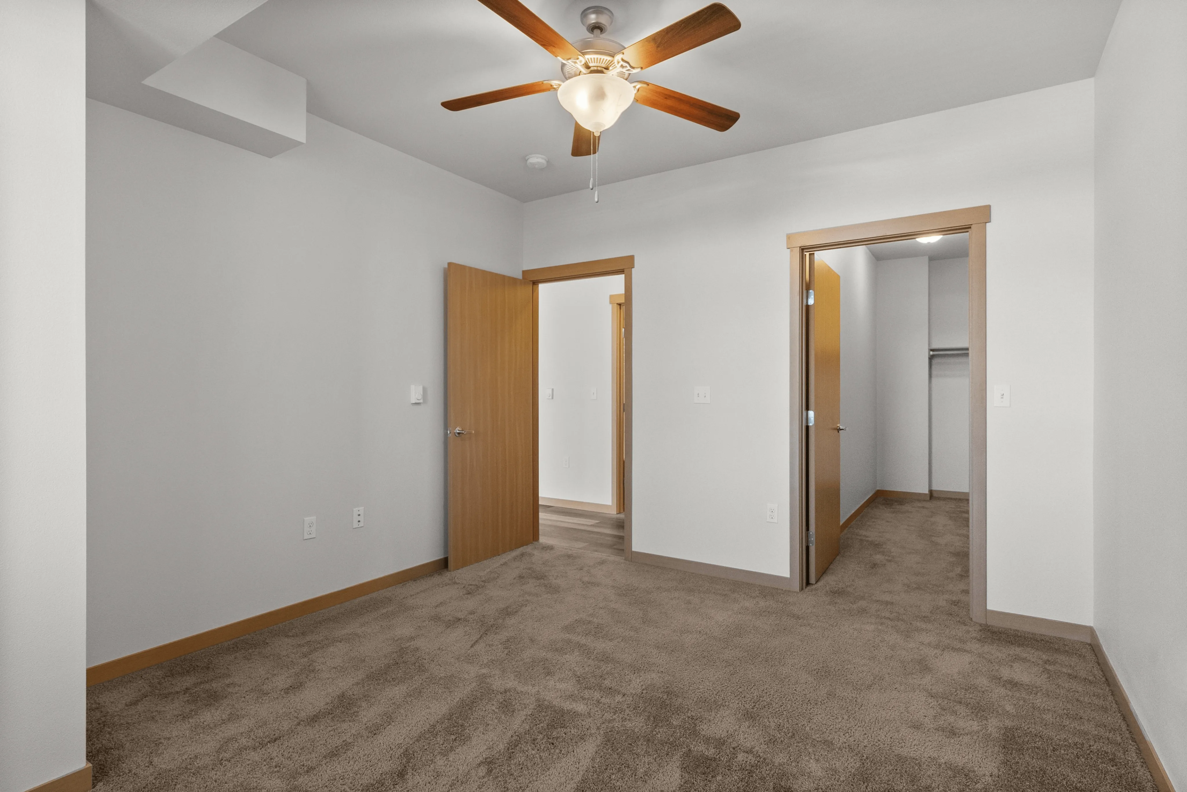 Charming bedroom with plush carpet, ceiling fan, and walk-in closet.