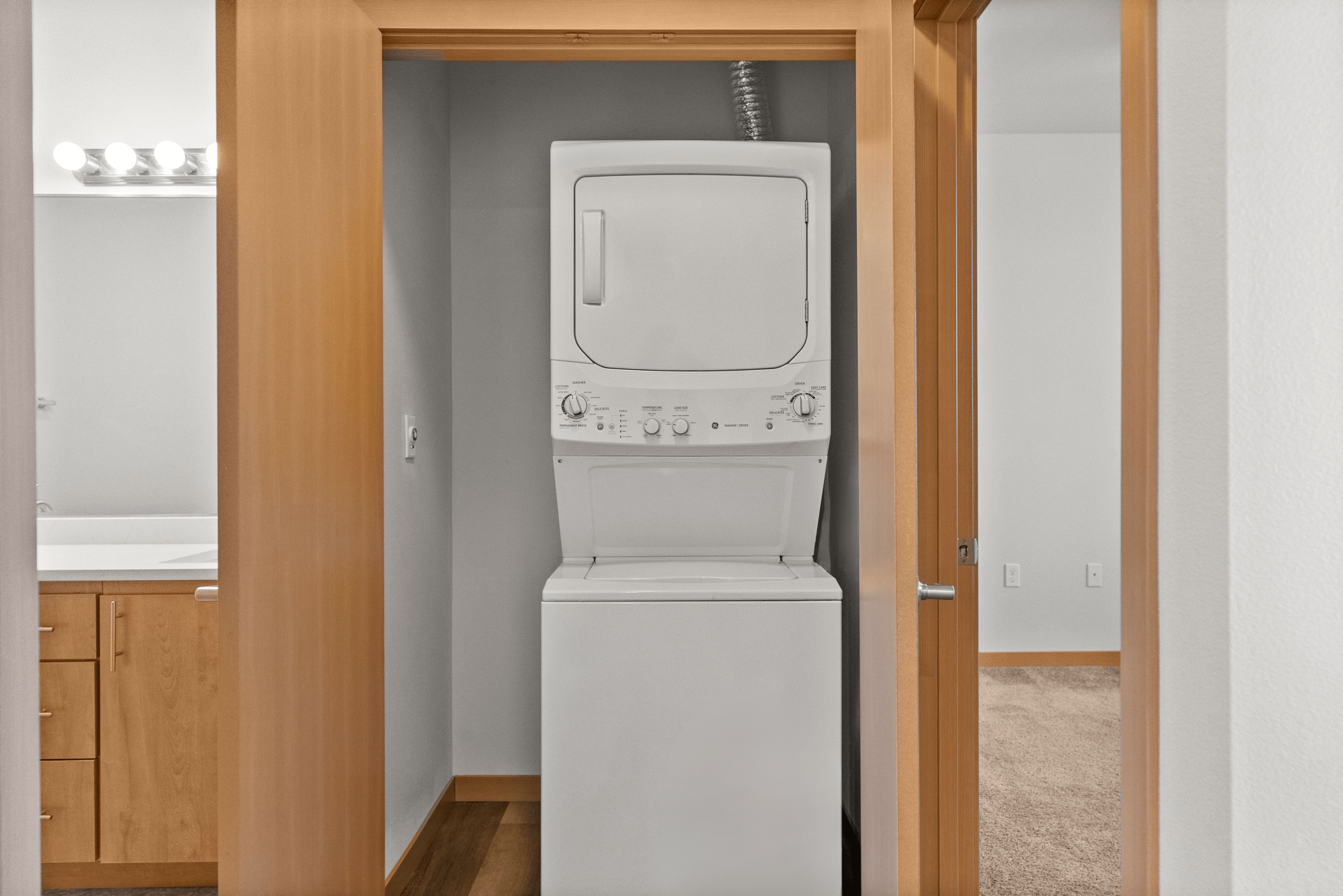 Compact laundry area featuring a modern stacked washer and dryer conveniently located in a spacious apartment.