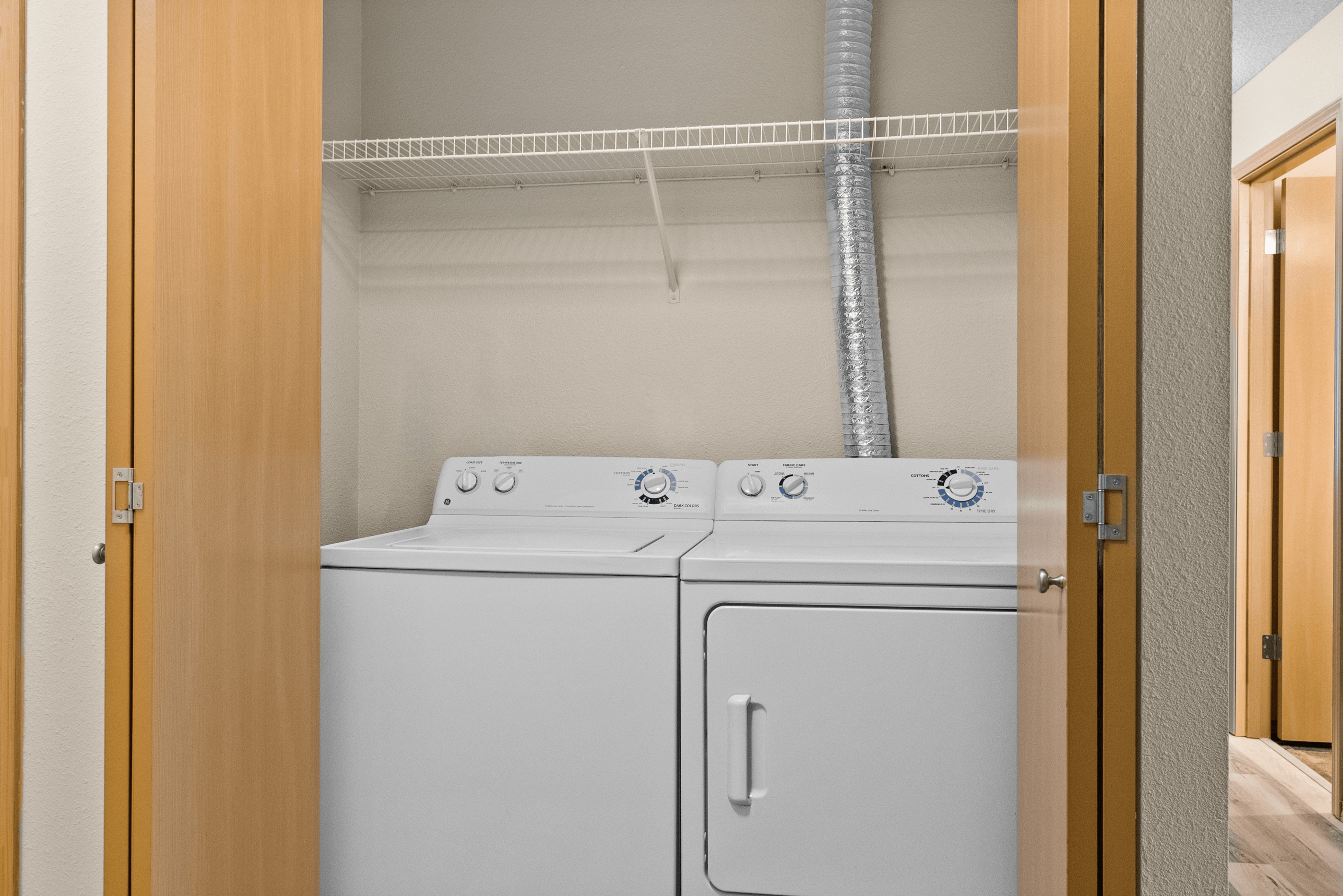 Modern laundry area with washer and dryer, featuring sleek wood-paneled doors and convenient shelving.