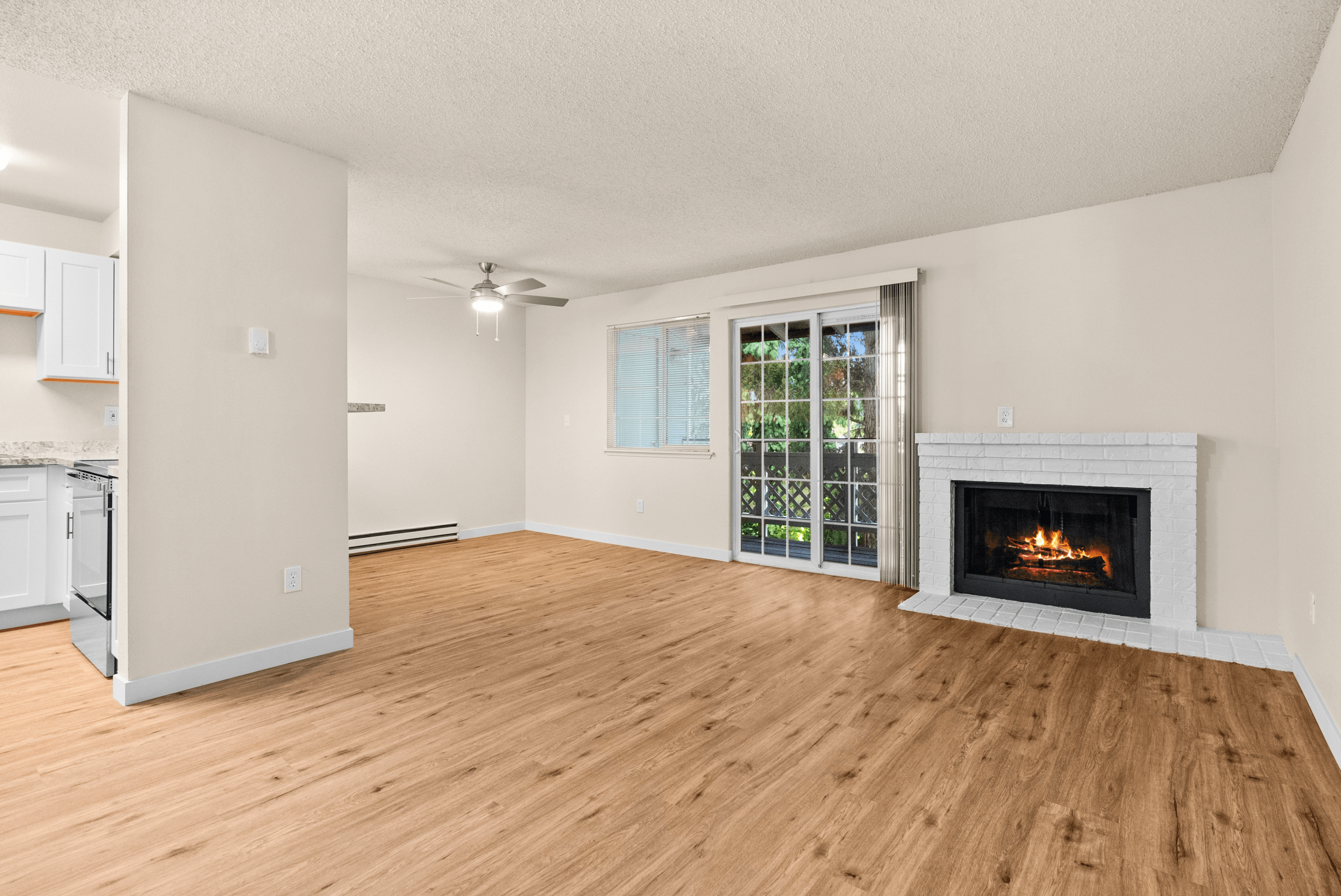 Bright and inviting living space featuring a cozy fireplace, elegant wood flooring, and large sliding glass doors with garden views.