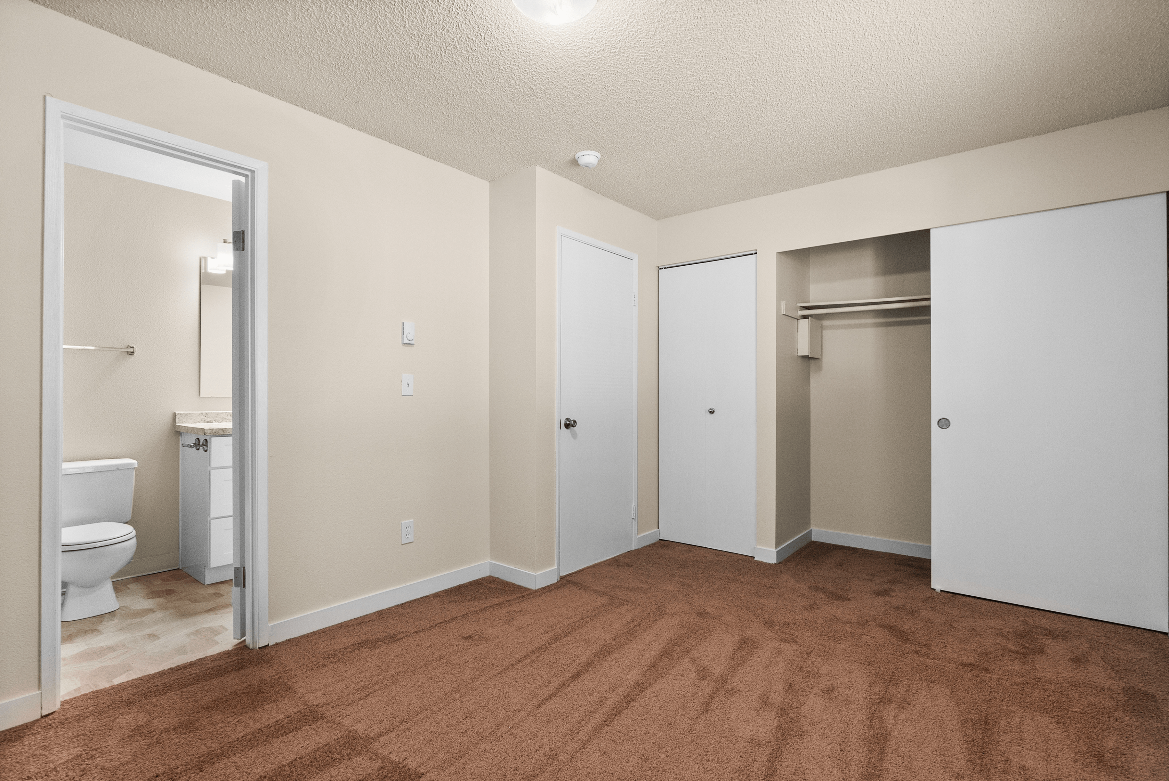 Carpeted bedroom with large closet and access to ensuite bathroom.