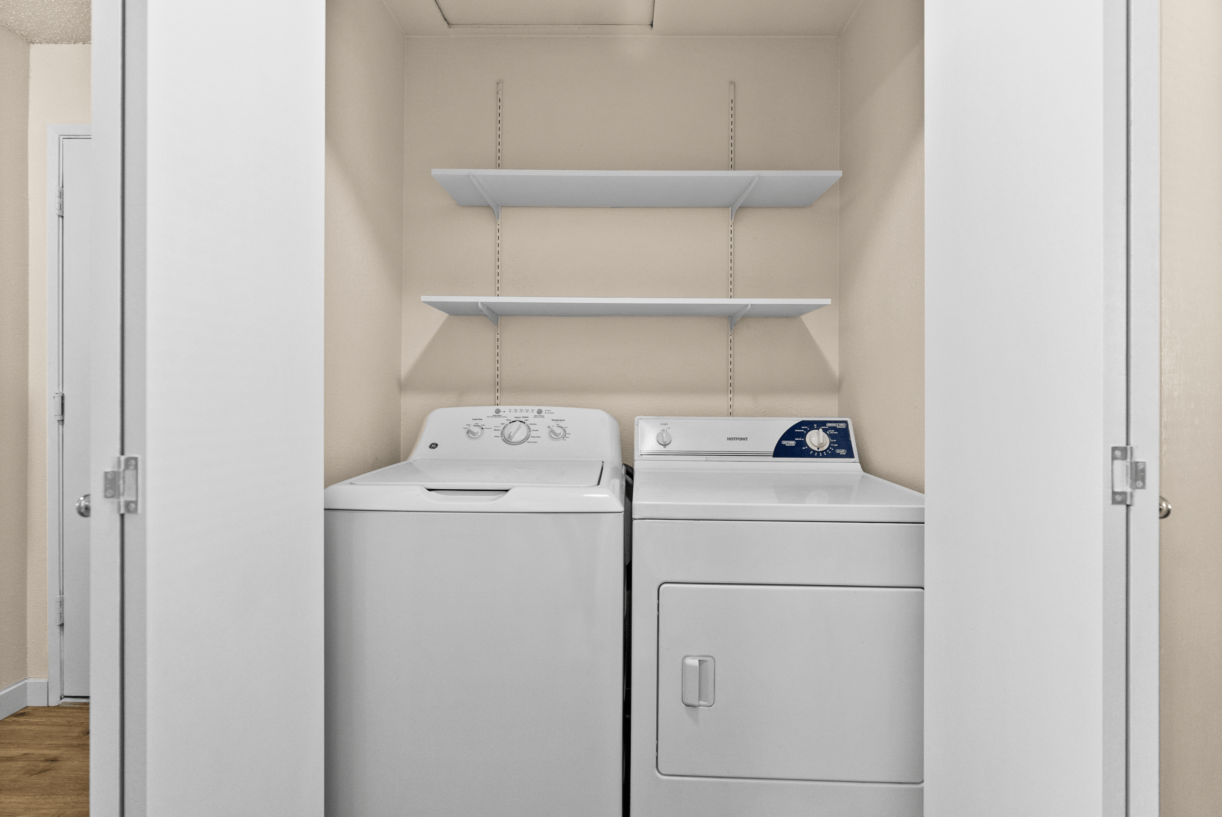 Efficient laundry area with a washer and dryer, complemented by convenient overhead shelving for storage.