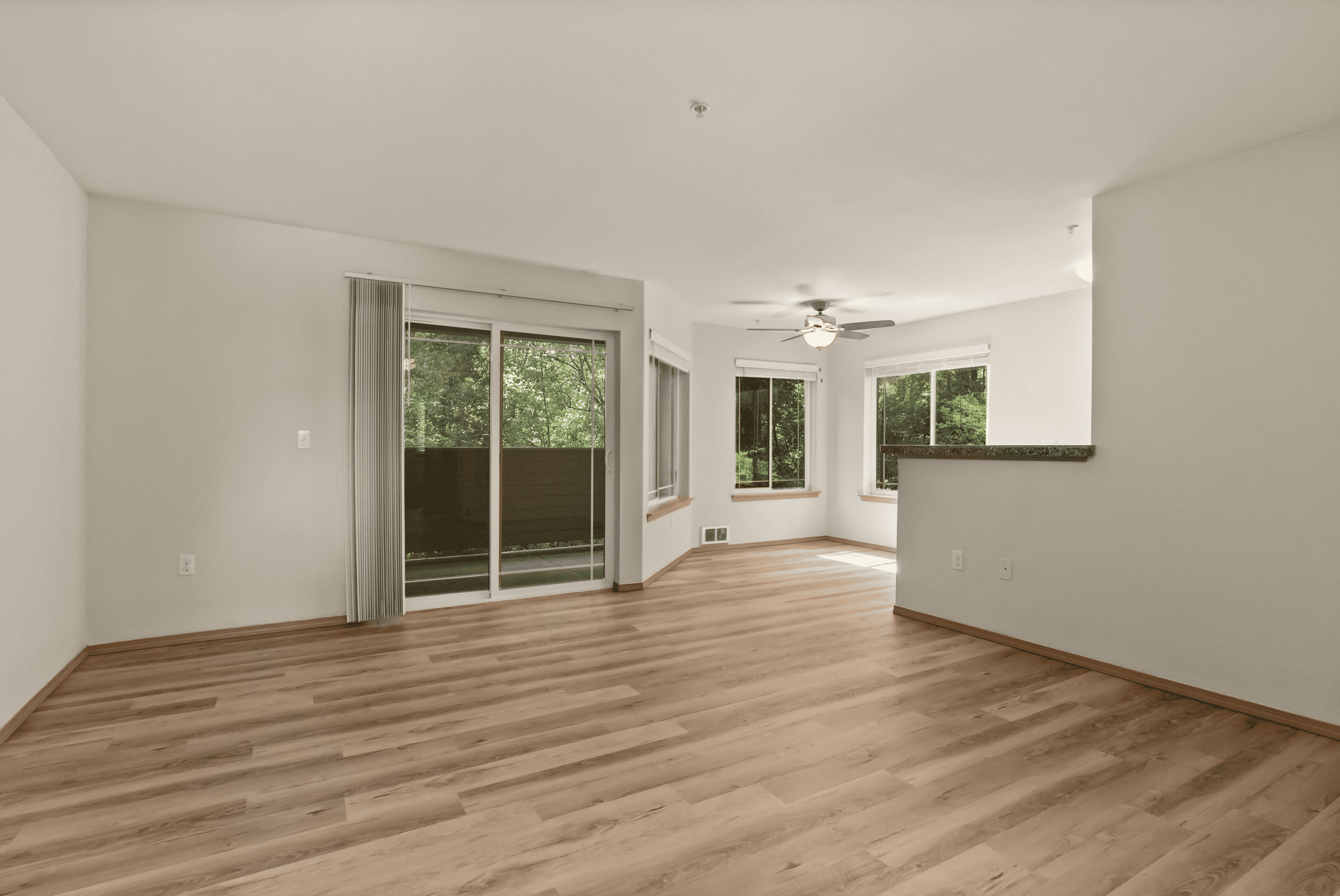 Bright and spacious open-concept living area with elegant hardwood flooring, large windows, and a cozy balcony view.