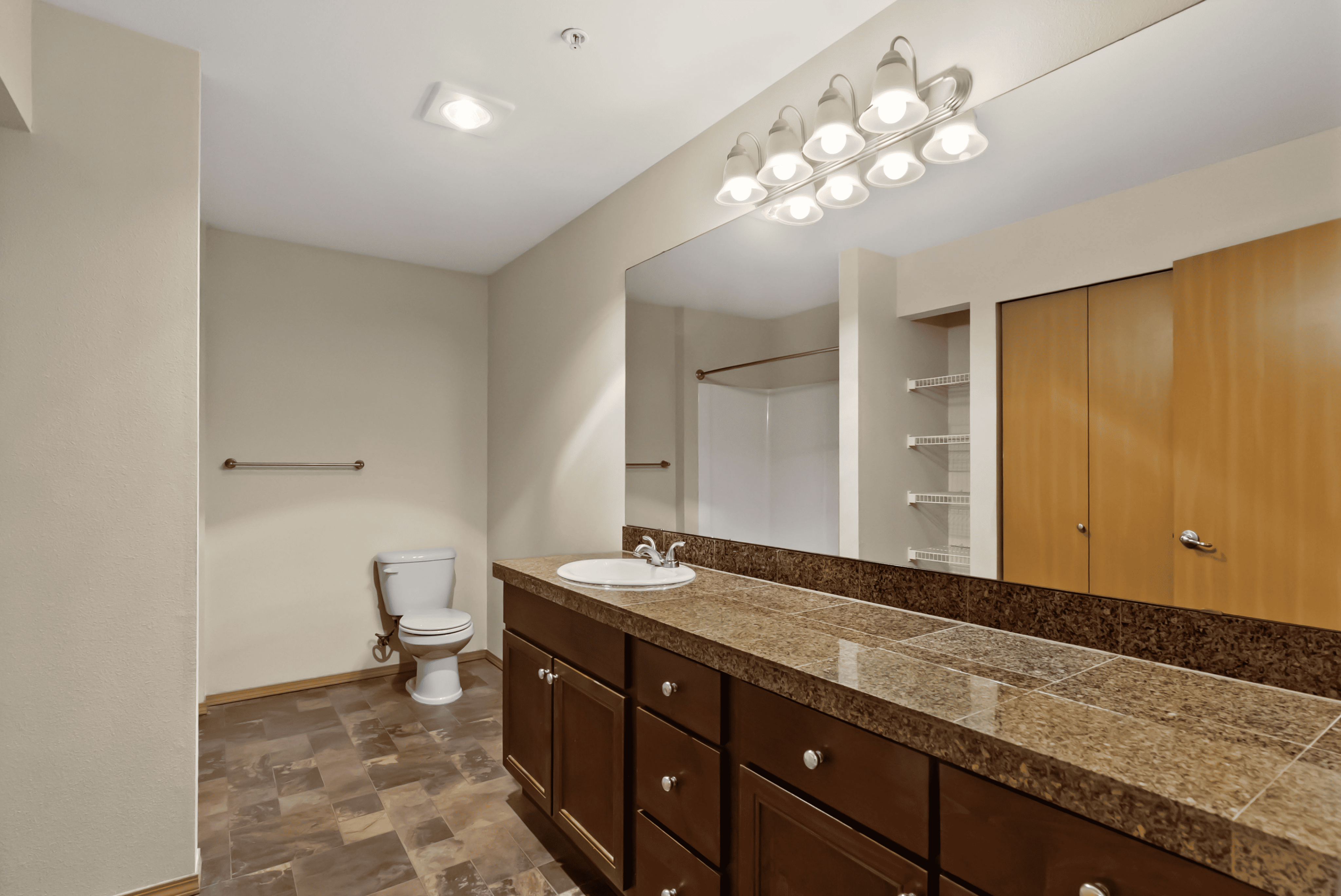 Elegant bathroom with spacious granite countertop, ample cabinet storage, and modern lighting fixtures.