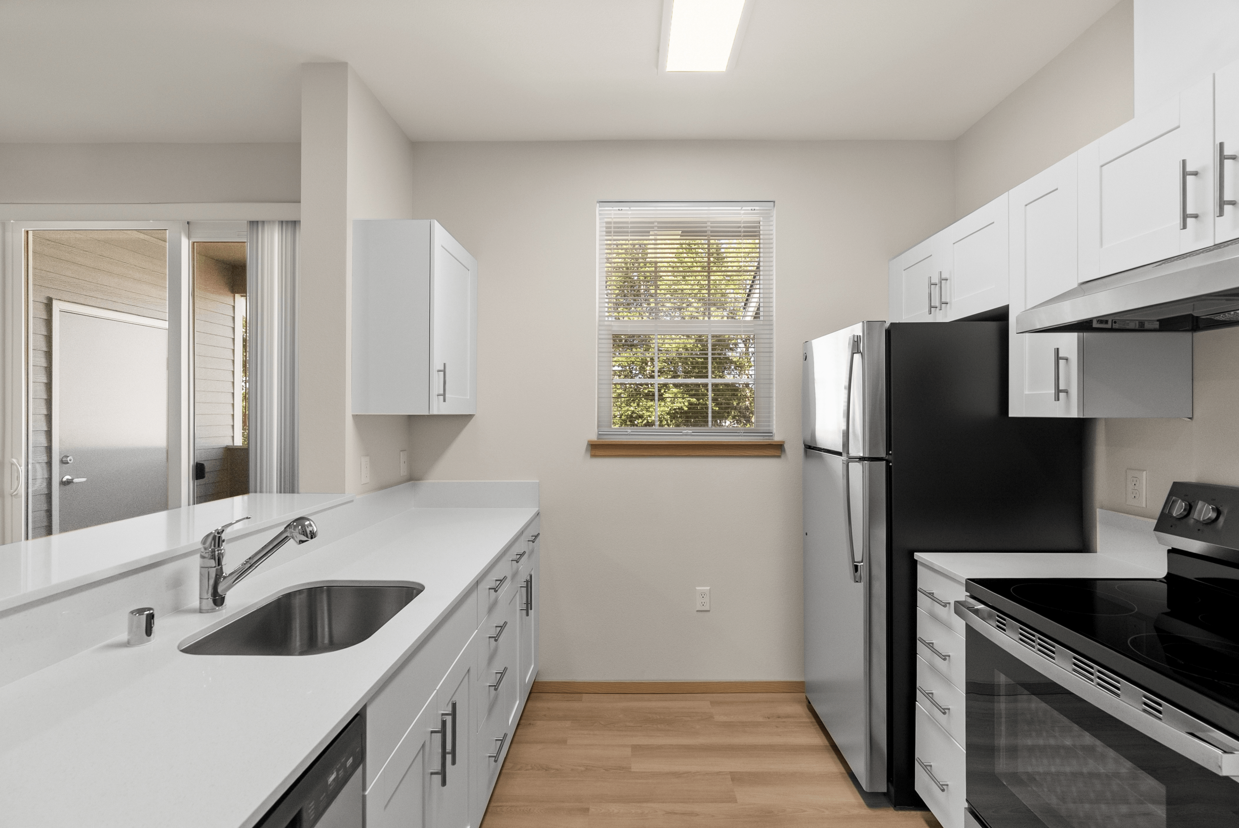Modern kitchen with sleek white cabinetry, stainless steel appliances, and ample natural light.