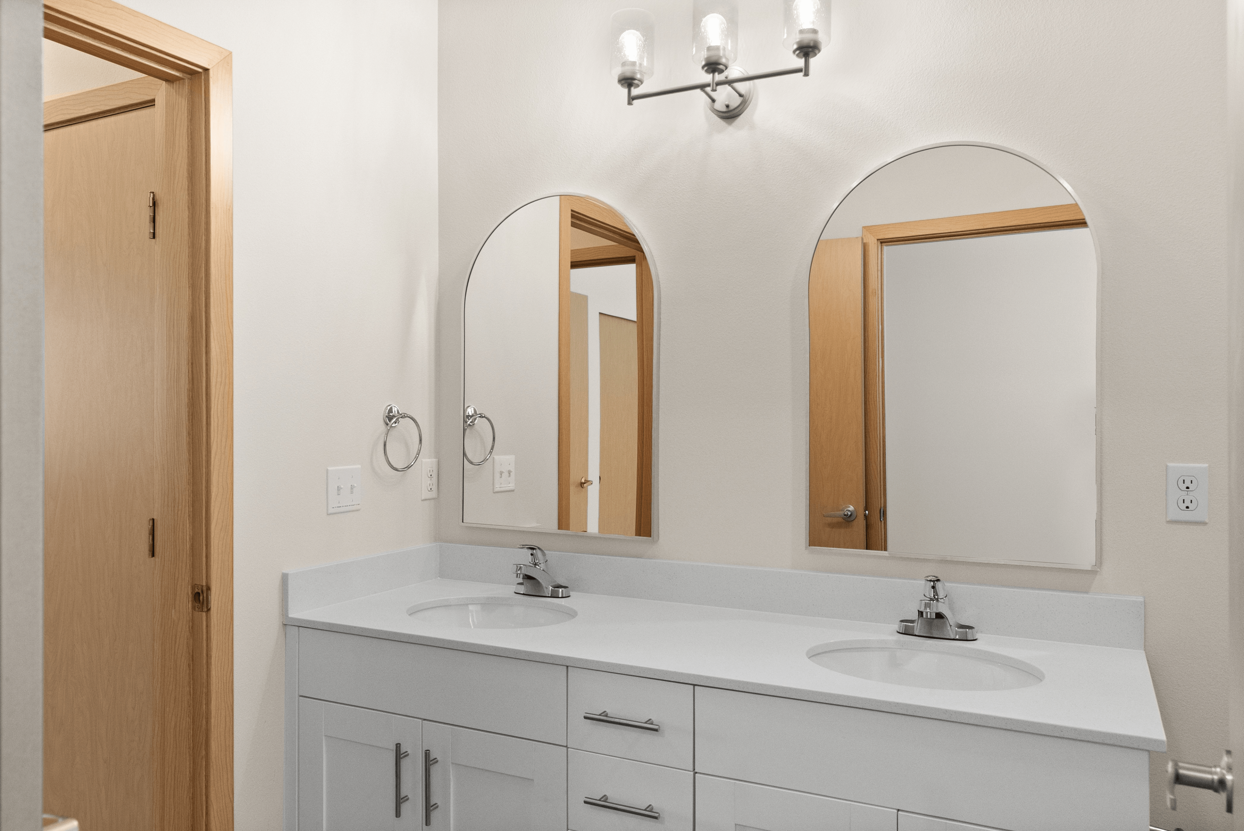 Elegant bathroom with dual sinks, modern fixtures, and stylish mirrors enhancing a bright, sophisticated ambiance.