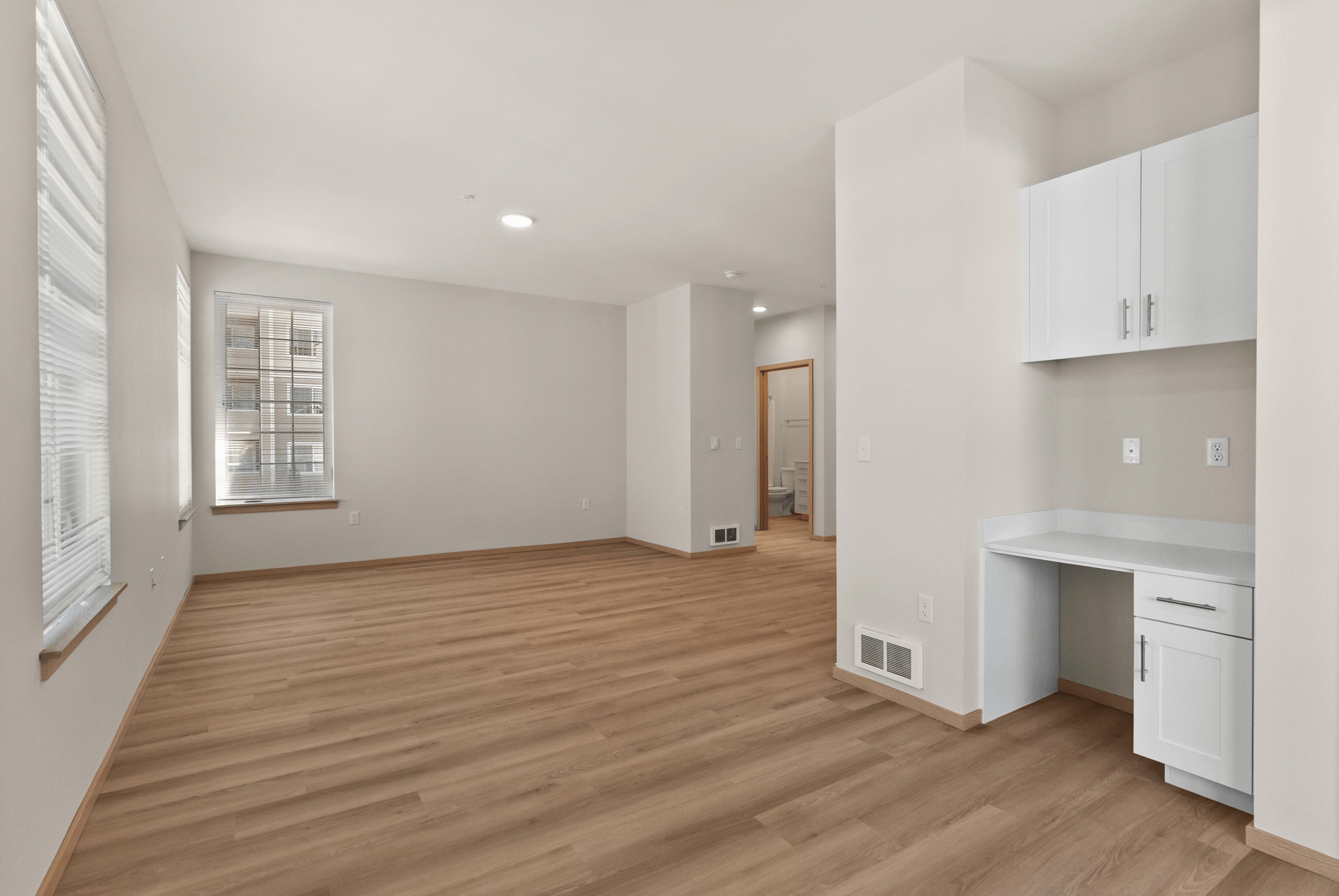 Bright, open-plan interior with wood flooring, large windows, and built-in cabinetry for a modern and inviting living space.