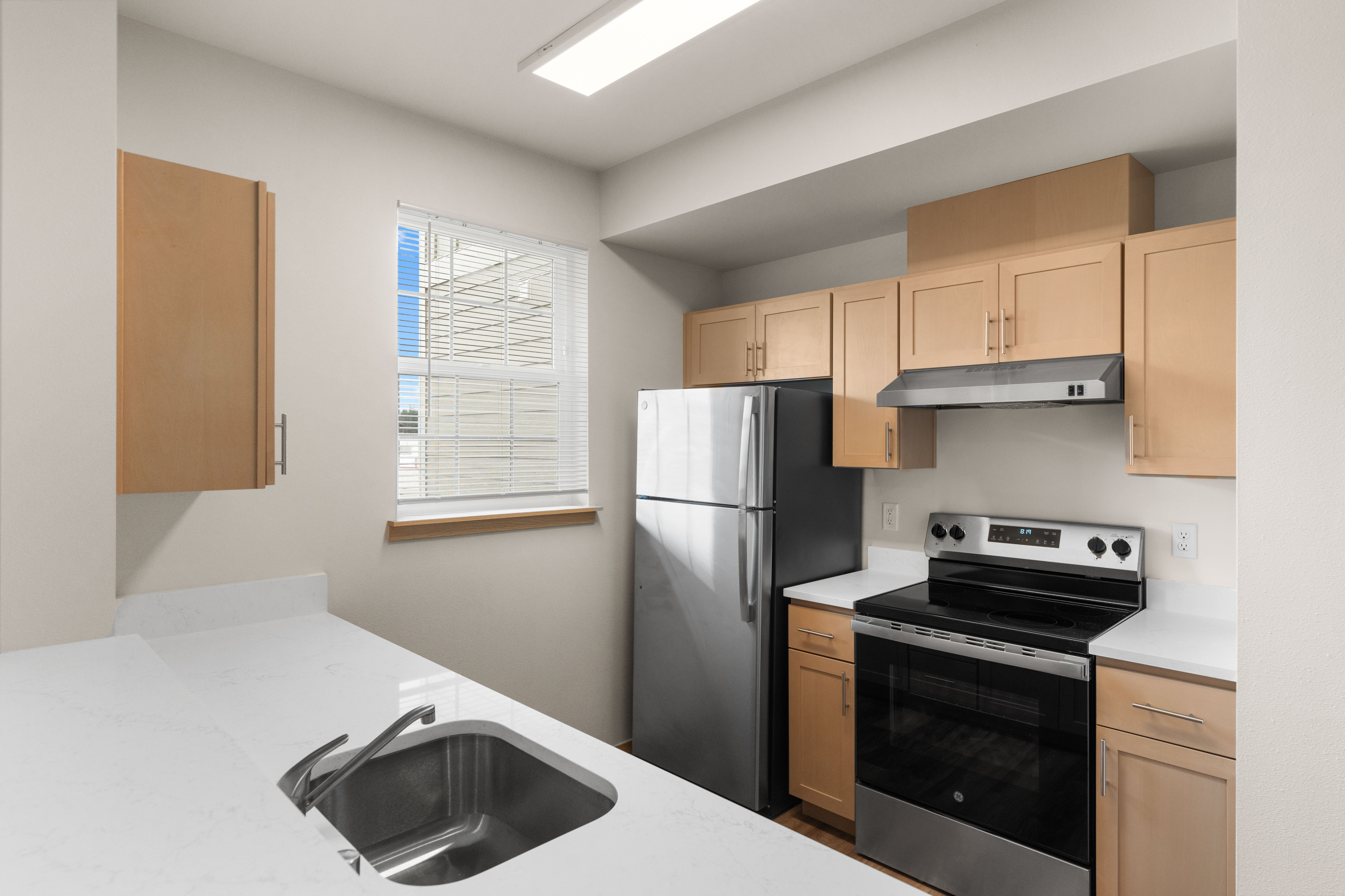 Modern kitchen featuring stainless steel appliances, sleek cabinetry, and a bright window for natural light.