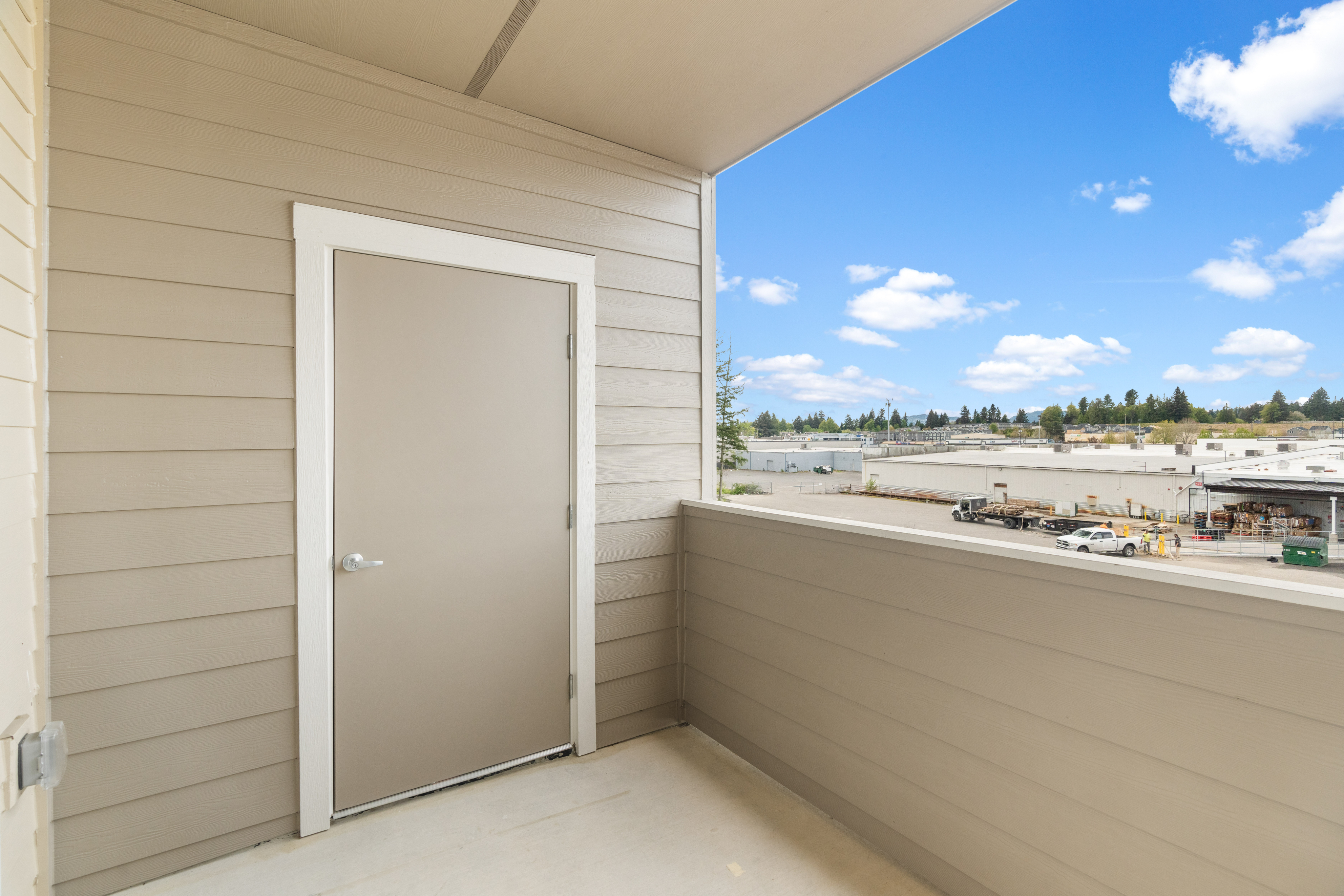 Bright balcony with modern siding and a scenic industrial view, perfect for relaxation and enjoying the outdoors.