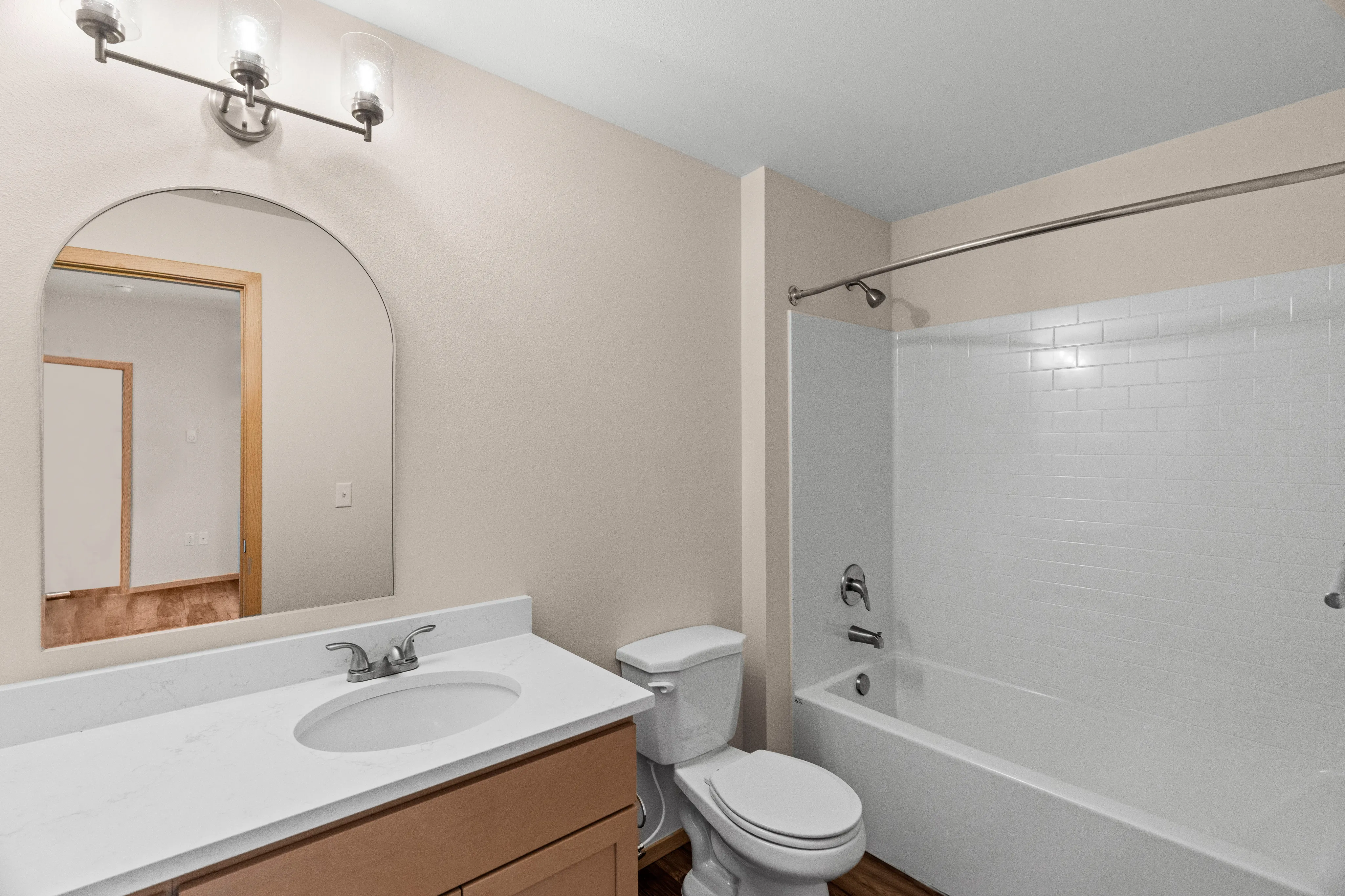 Elegant bathroom with a modern vanity, sleek mirror, and pristine white bath featuring stylish lighting.
