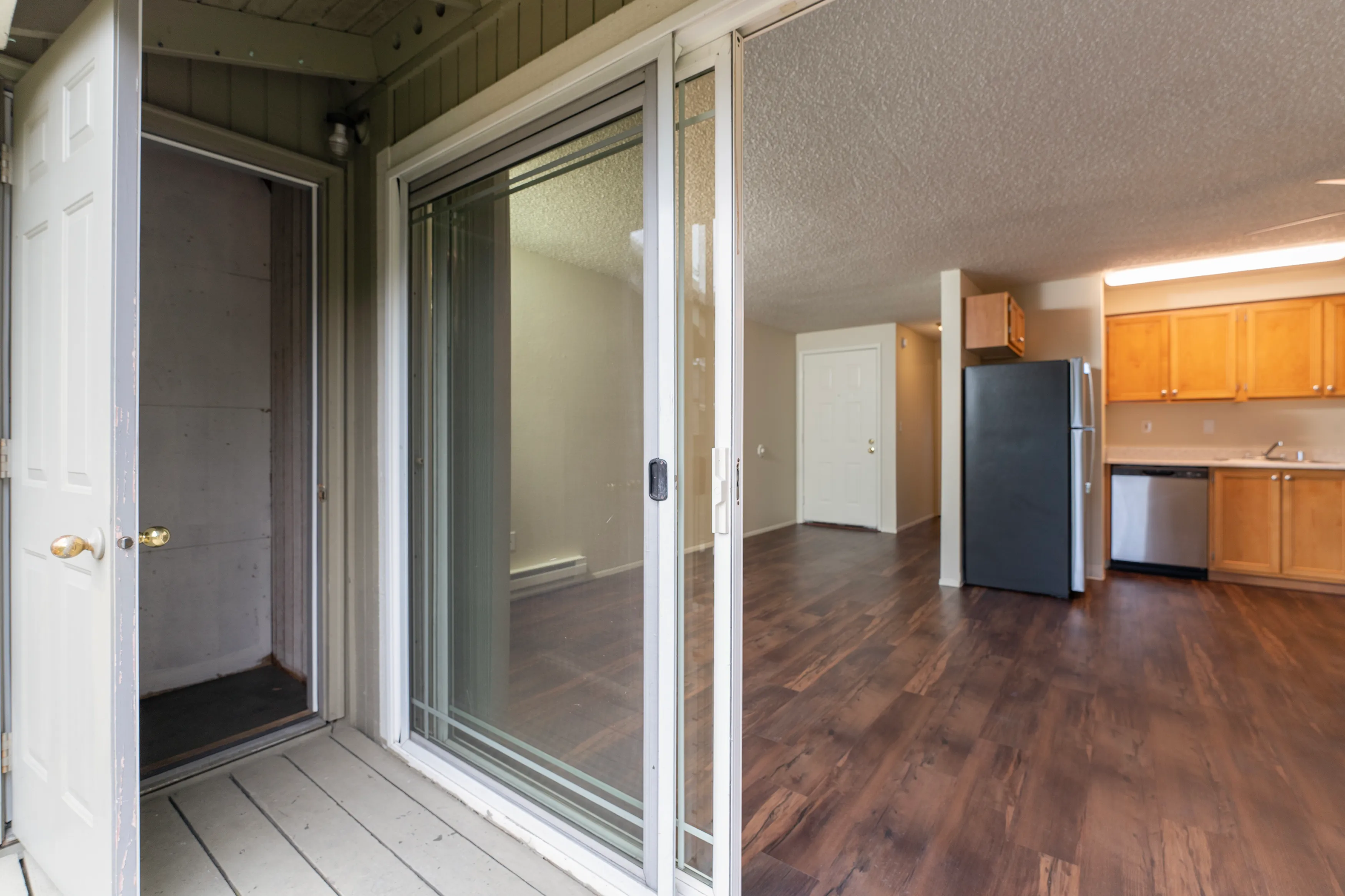 Bright and inviting open-concept living space featuring sleek hardwood floors, modern kitchen, and sliding glass doors leading to a cozy patio.