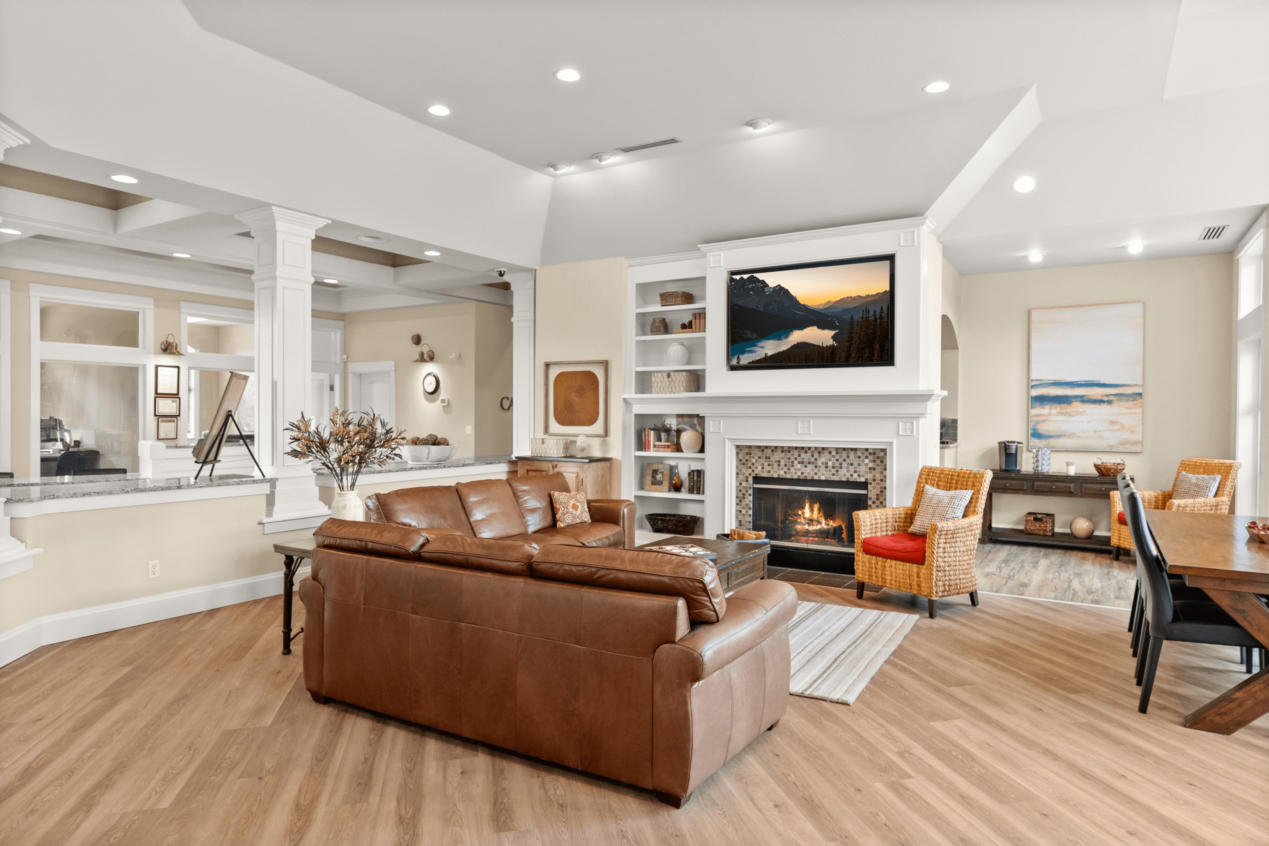 Inviting living room with elegant wood flooring and a cozy fireplace, featuring a leather sofa, stylish armchairs, and tasteful decor.