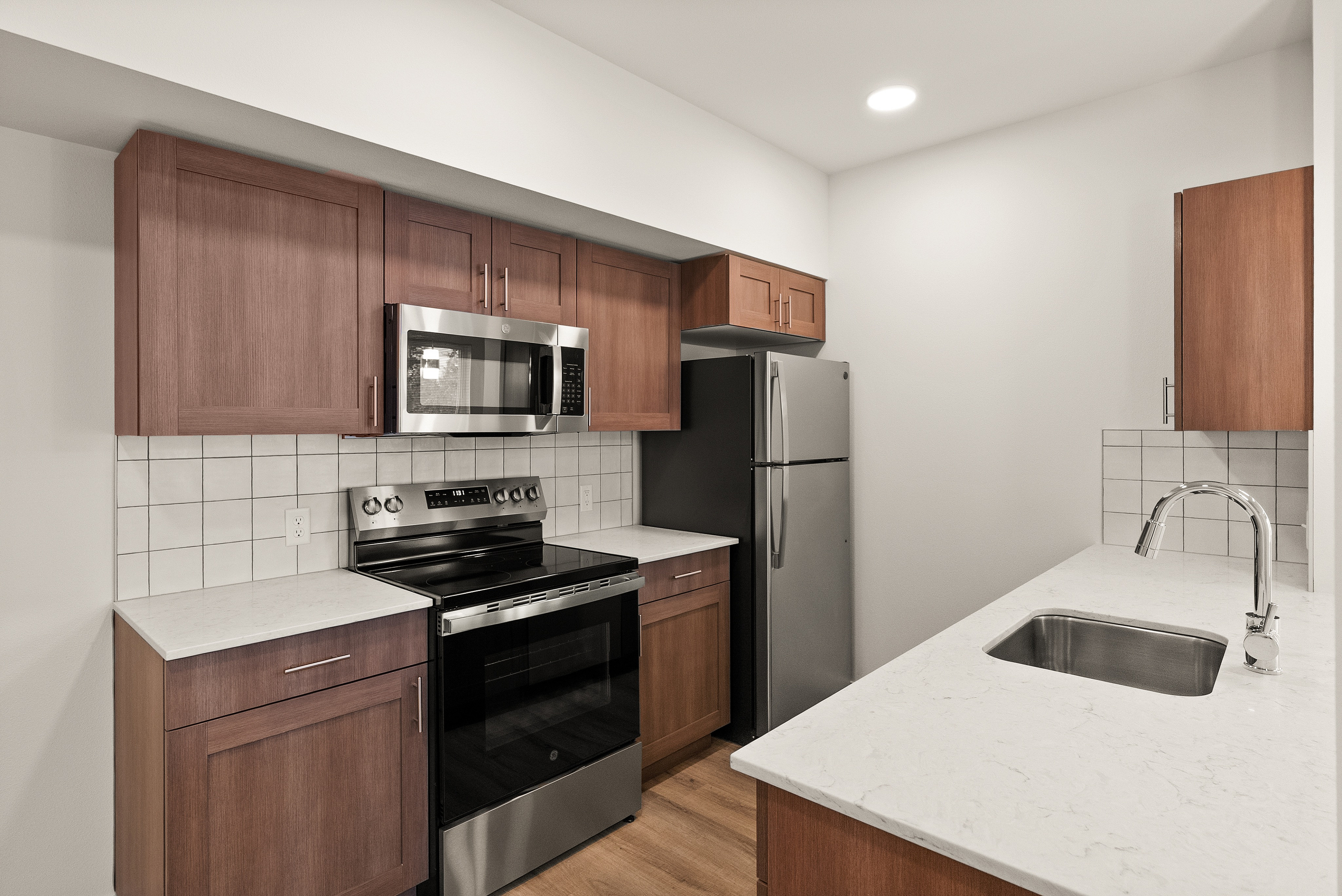 Modern kitchen with sleek stainless steel appliances, elegant wood cabinetry, and a chic white countertop.