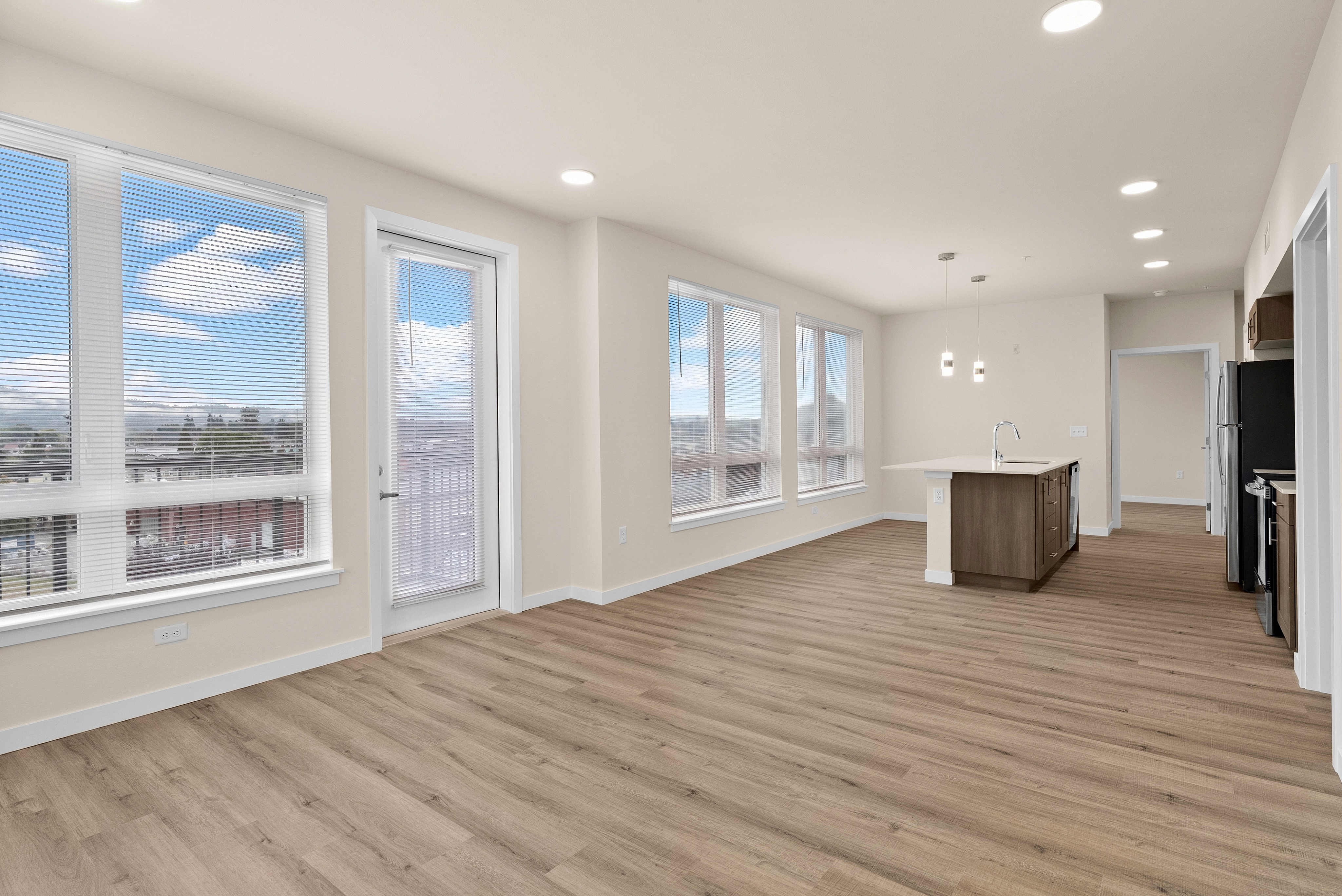 Bright, open-concept living space with hardwood floors, large windows, and modern kitchen island.