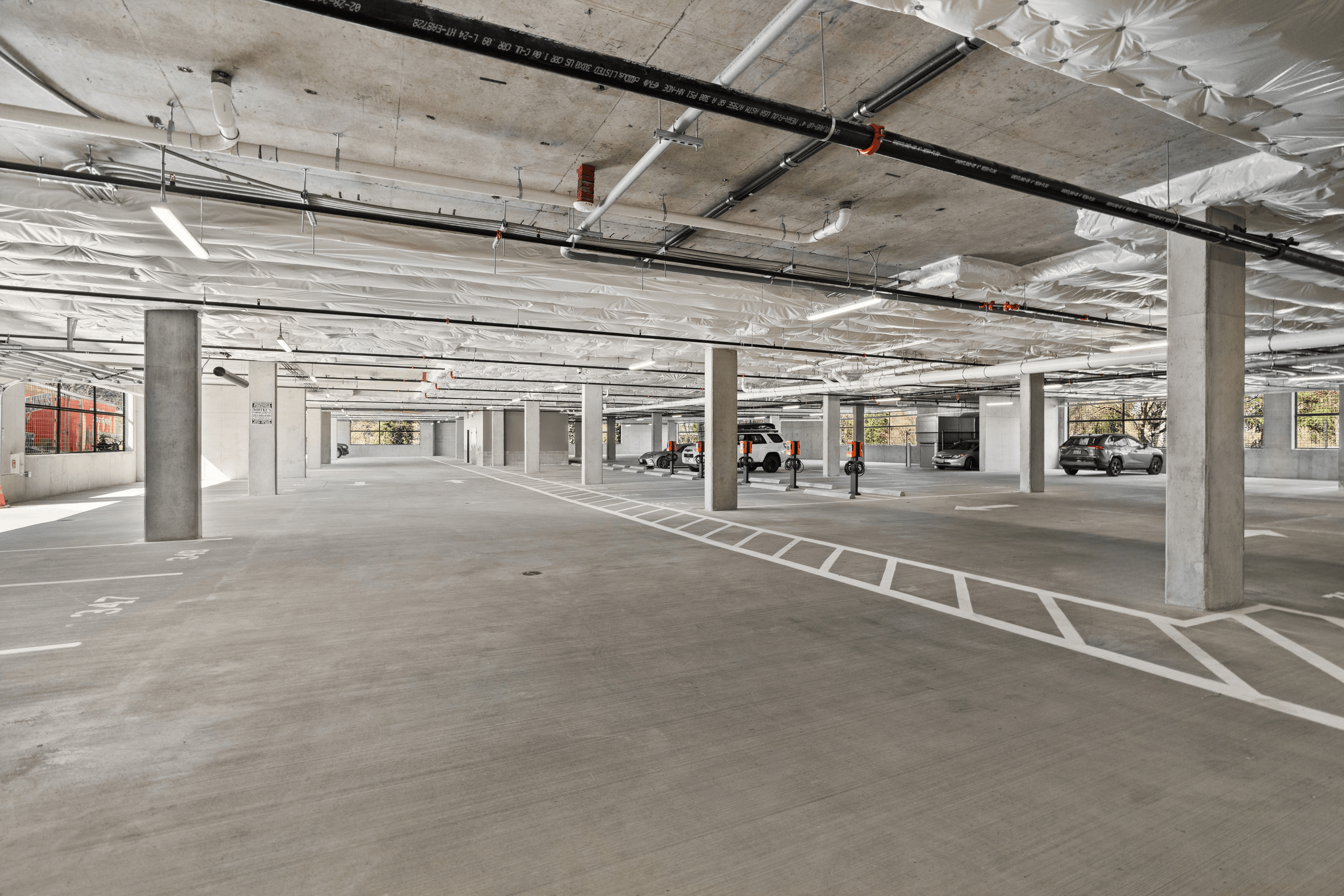 Modern and spacious underground parking garage featuring ample lighting and convenient vehicle charging stations.
