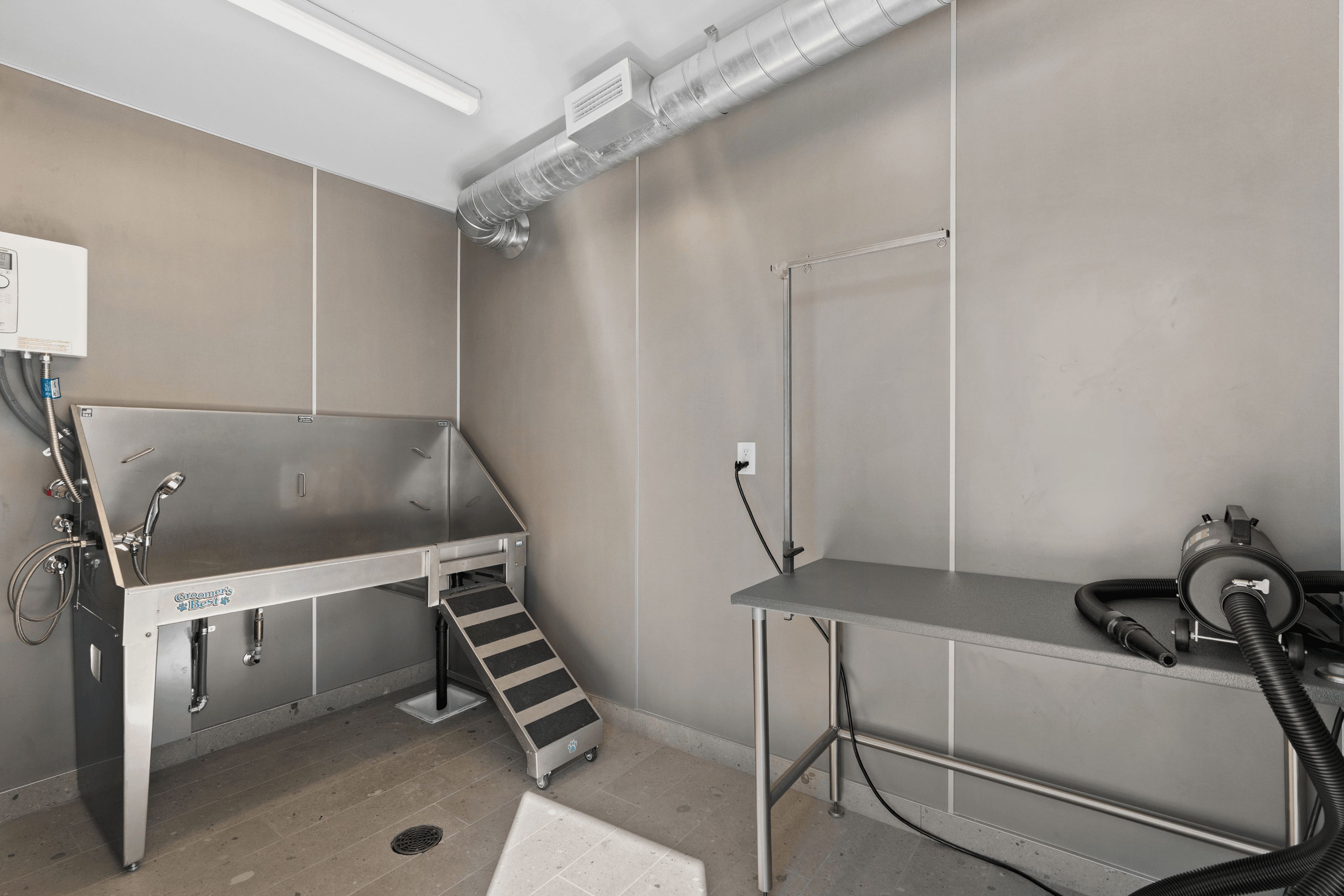 Modern pet grooming station featuring a large wash basin, convenient ramp, and sleek grooming table with dryer.