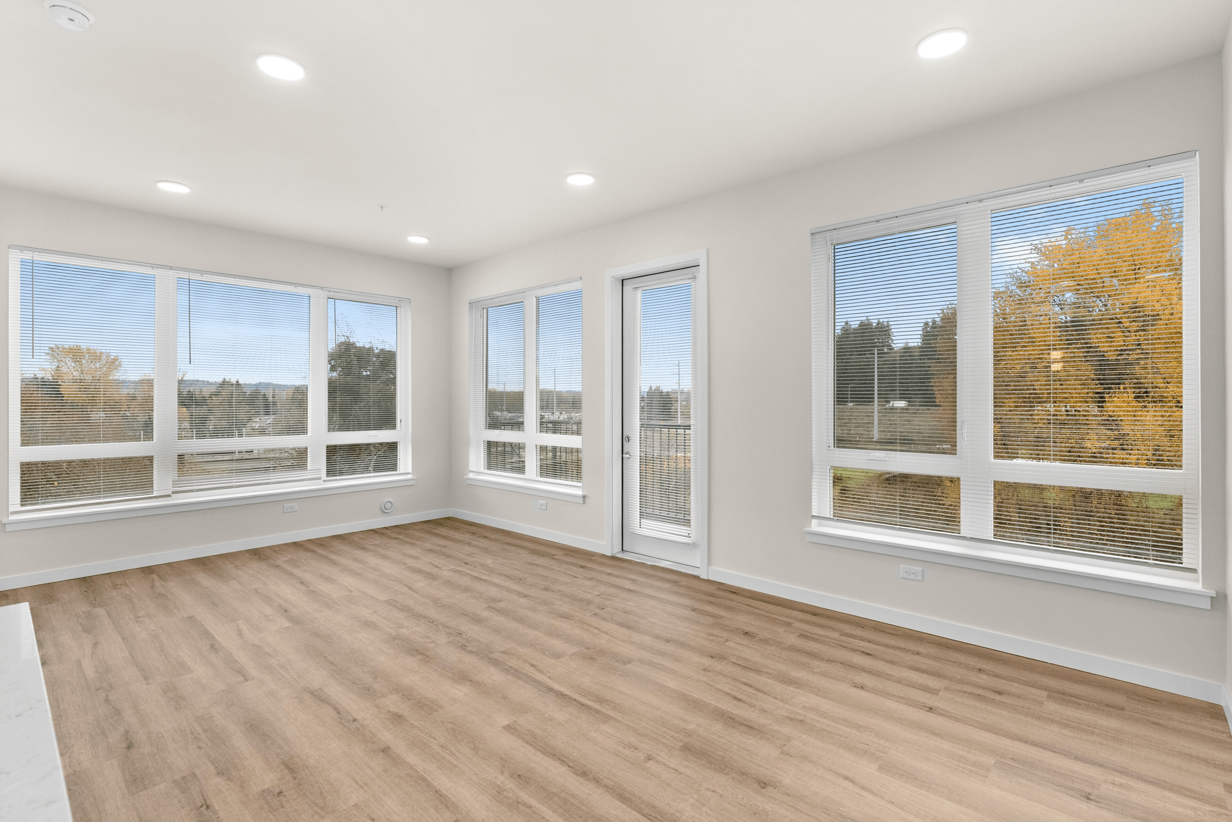 Bright and inviting apartment space with large windows, offering scenic outdoor views and abundant natural light.