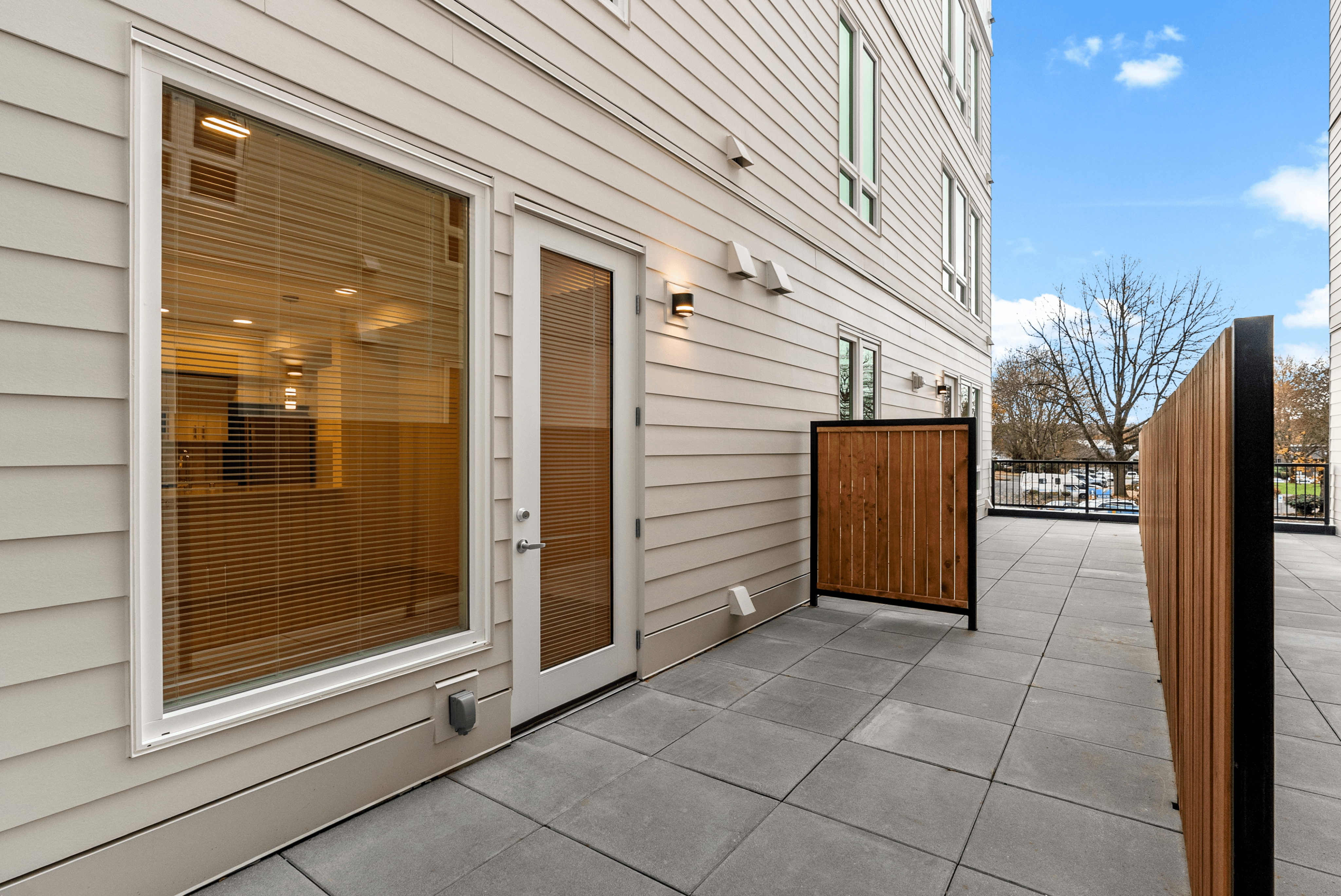 Chic modern patio with sleek fencing and large window, offering a bright and inviting atmosphere perfect for relaxation.