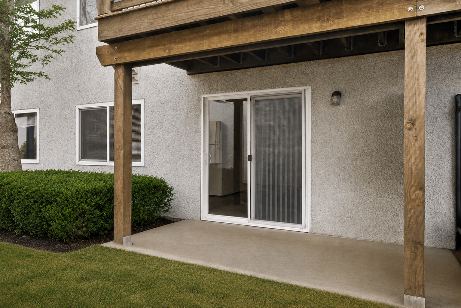Charming patio with sliding glass doors and natural greenery perfect for relaxation.