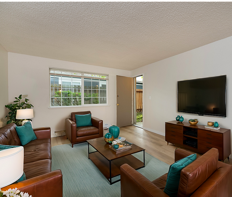 Spacious living room with stylish brown leather sofas, a modern entertainment unit, and teal accents.