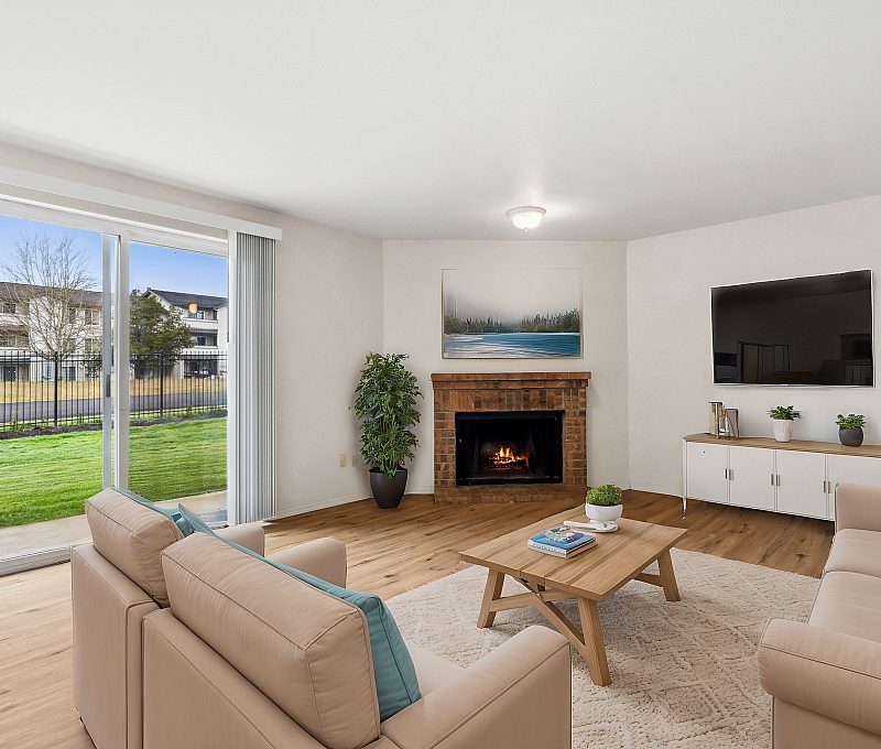 Bright living room featuring a comfortable seating area, fireplace, and large sliding glass doors with outdoor views.