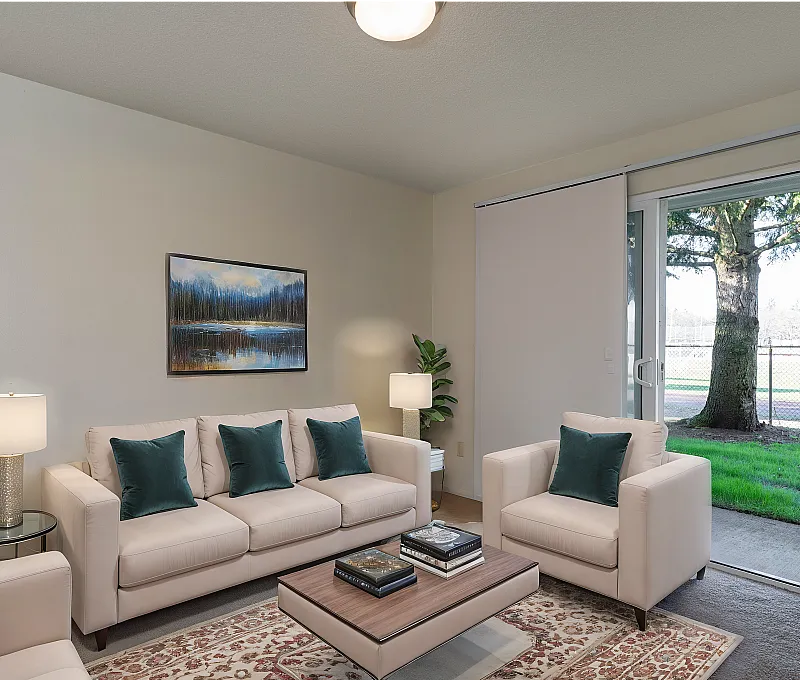 Bright and inviting living room with elegant cream sofas, teal accent pillows, and a picturesque window view, creating a cozy yet sophisticated ambiance.