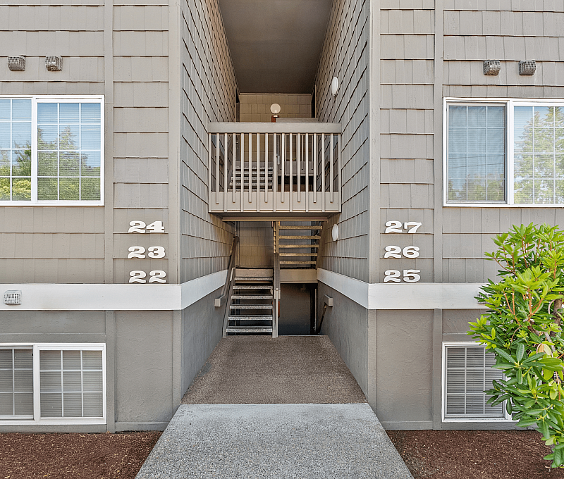 Modern apartment entrance with clean architectural design, featuring numbered units and well-maintained pathways.