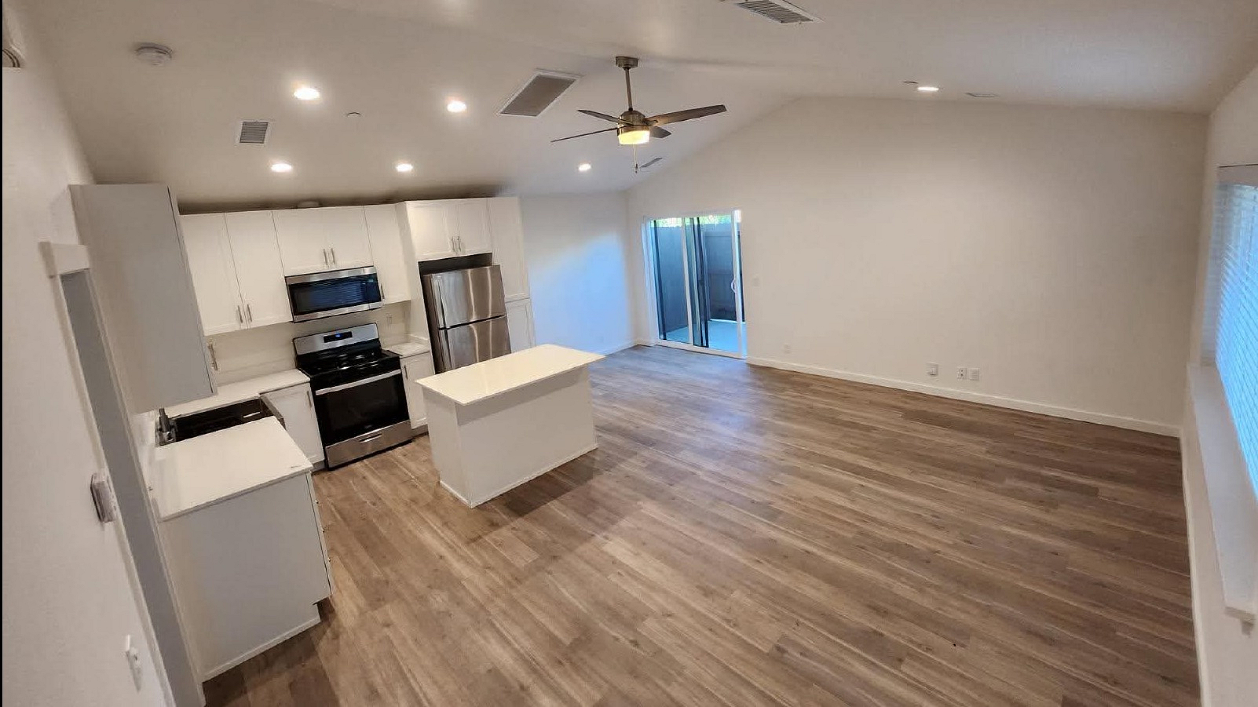 Modern open-plan apartment featuring a sleek kitchen with stainless steel appliances, elegant hardwood floors, and ample natural light.