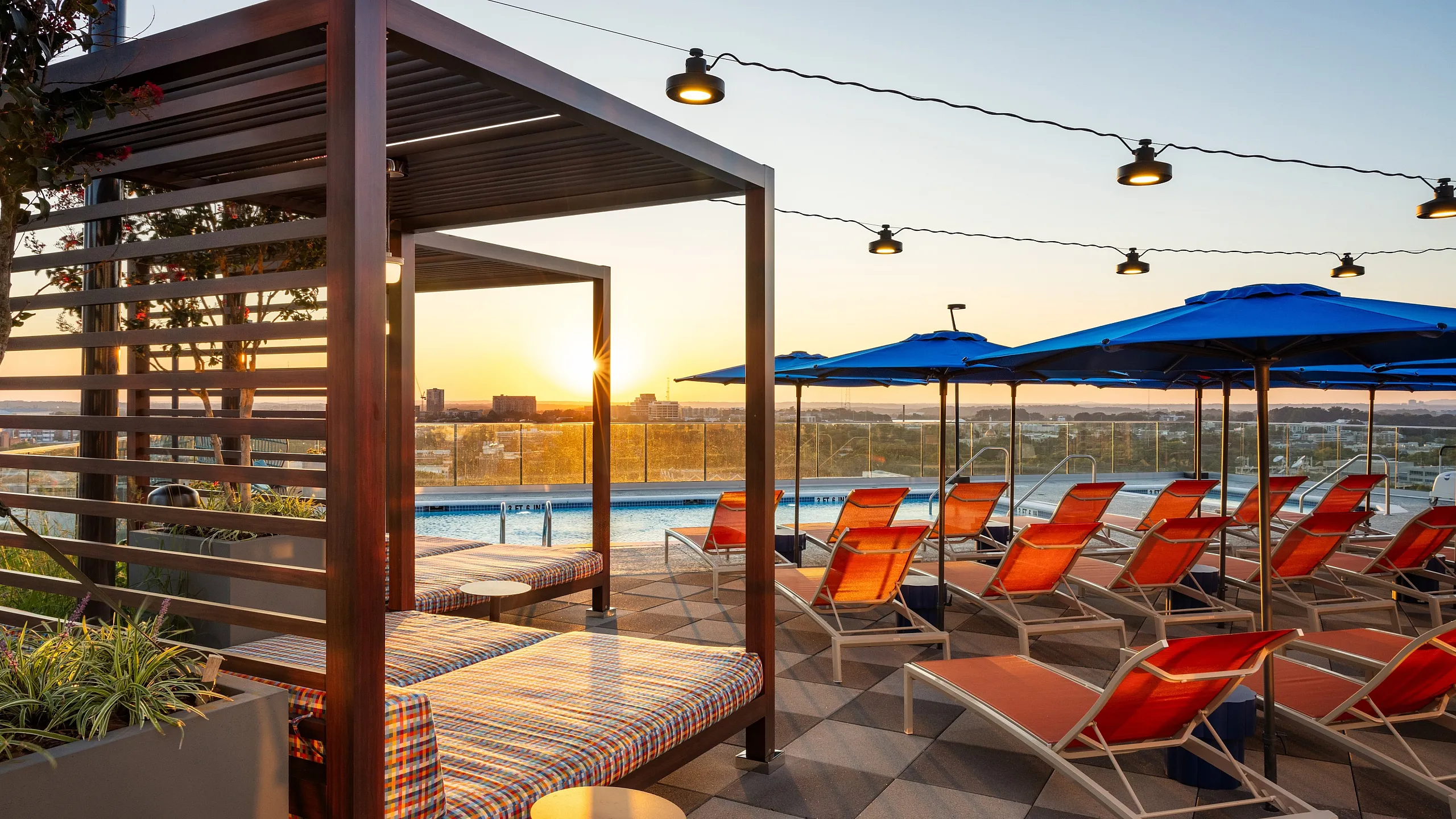 Stunning rooftop pool area with cozy cabanas, vibrant lounge chairs, and picturesque sunset views.