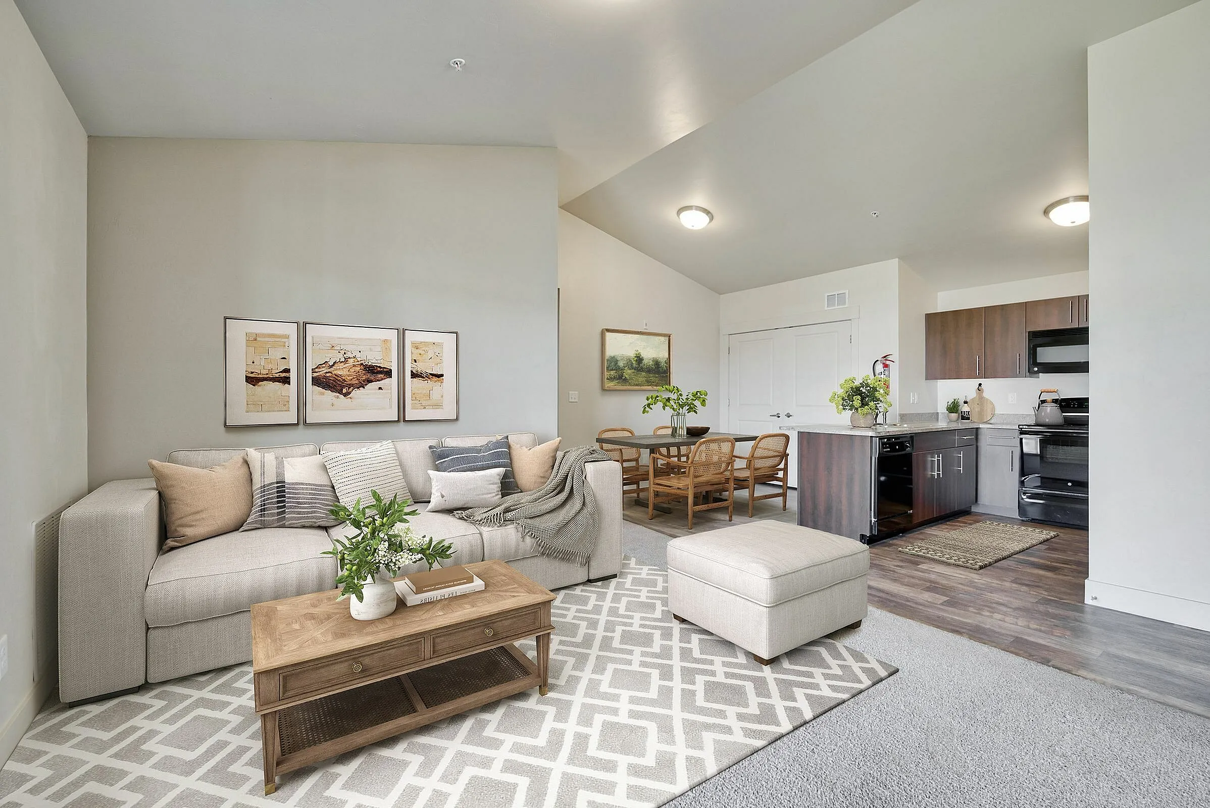 Cozy open-plan living room with stylish beige couch, elegant dining area, and modern kitchen with dark wood cabinetry.