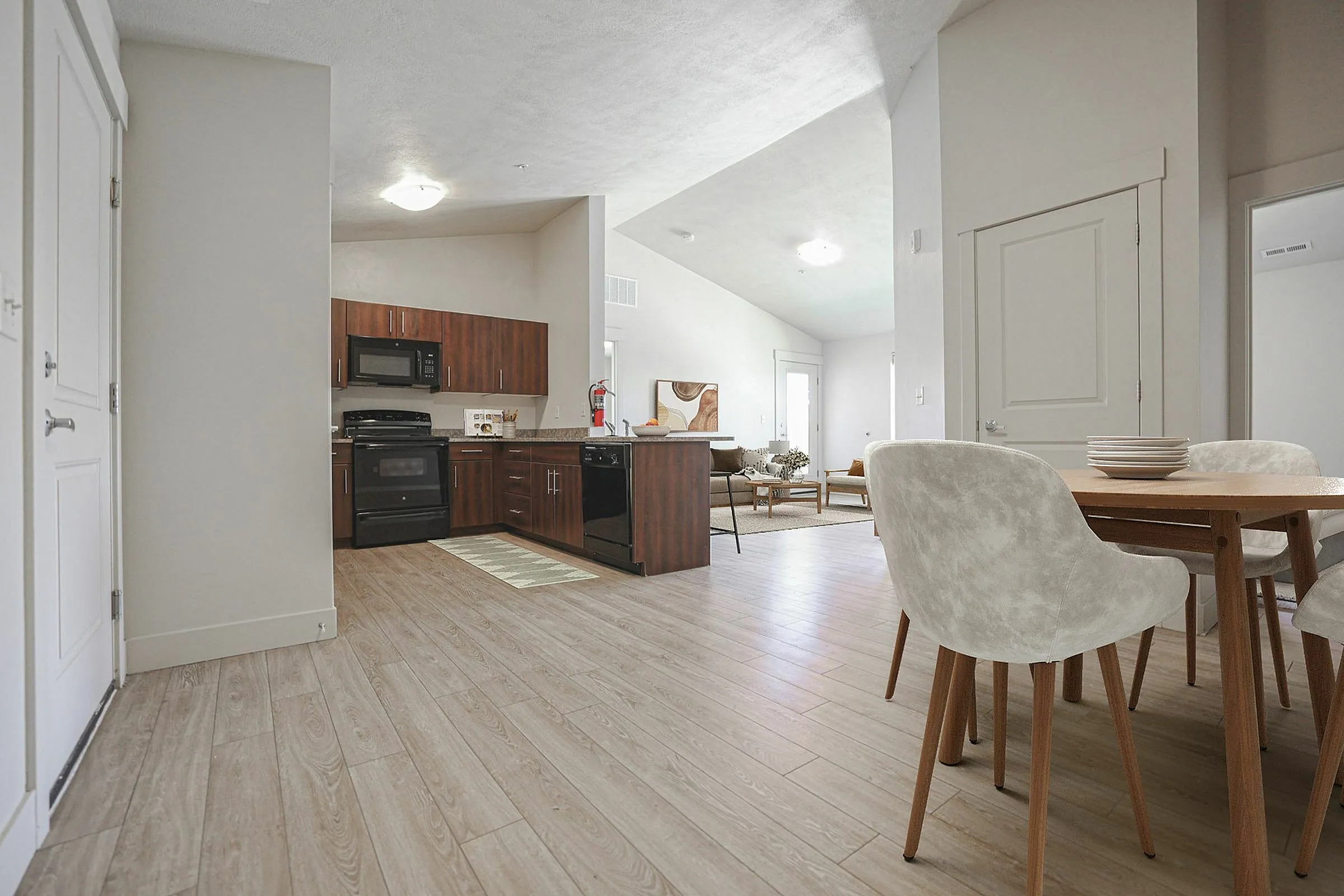 Modern apartment interior showcasing an open-concept kitchen and dining area with stylish wooden cabinetry, sleek appliances, and elegant flooring.