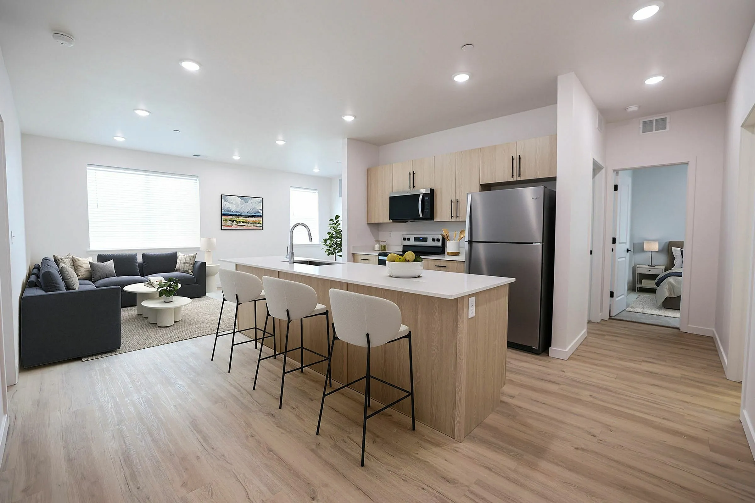 Modern open-concept kitchen and living area with sleek appliances, light wood flooring, and a cozy living space. Bright and welcoming ambiance with natural light.