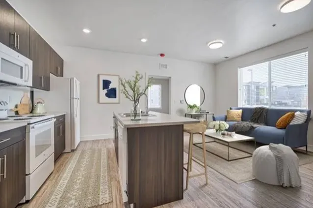 Modern open-concept living space with sleek kitchen, stylish island seating, and cozy lounge area filled with natural light.