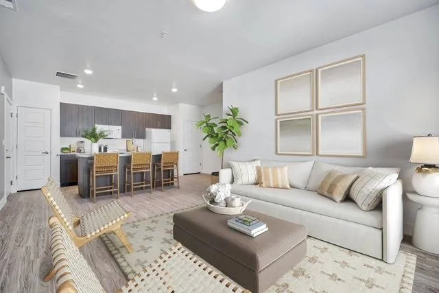 Bright and modern open-concept living area with stylish furnishings, hardwood floors, and a sleek kitchen with bar seating.