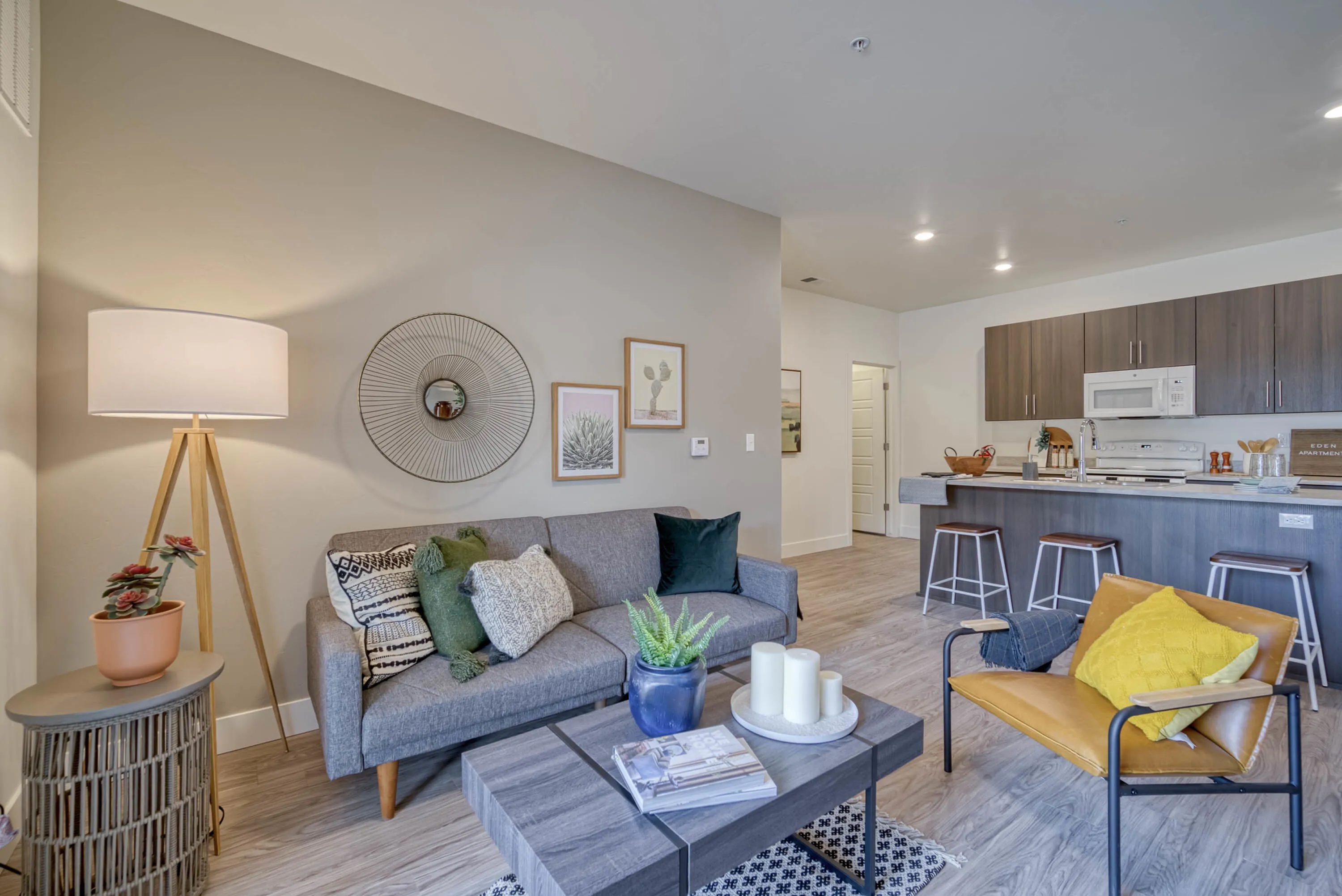 Chic open-concept living room with modern decor and cozy seating, seamlessly flowing into a stylish kitchen with bar seating.