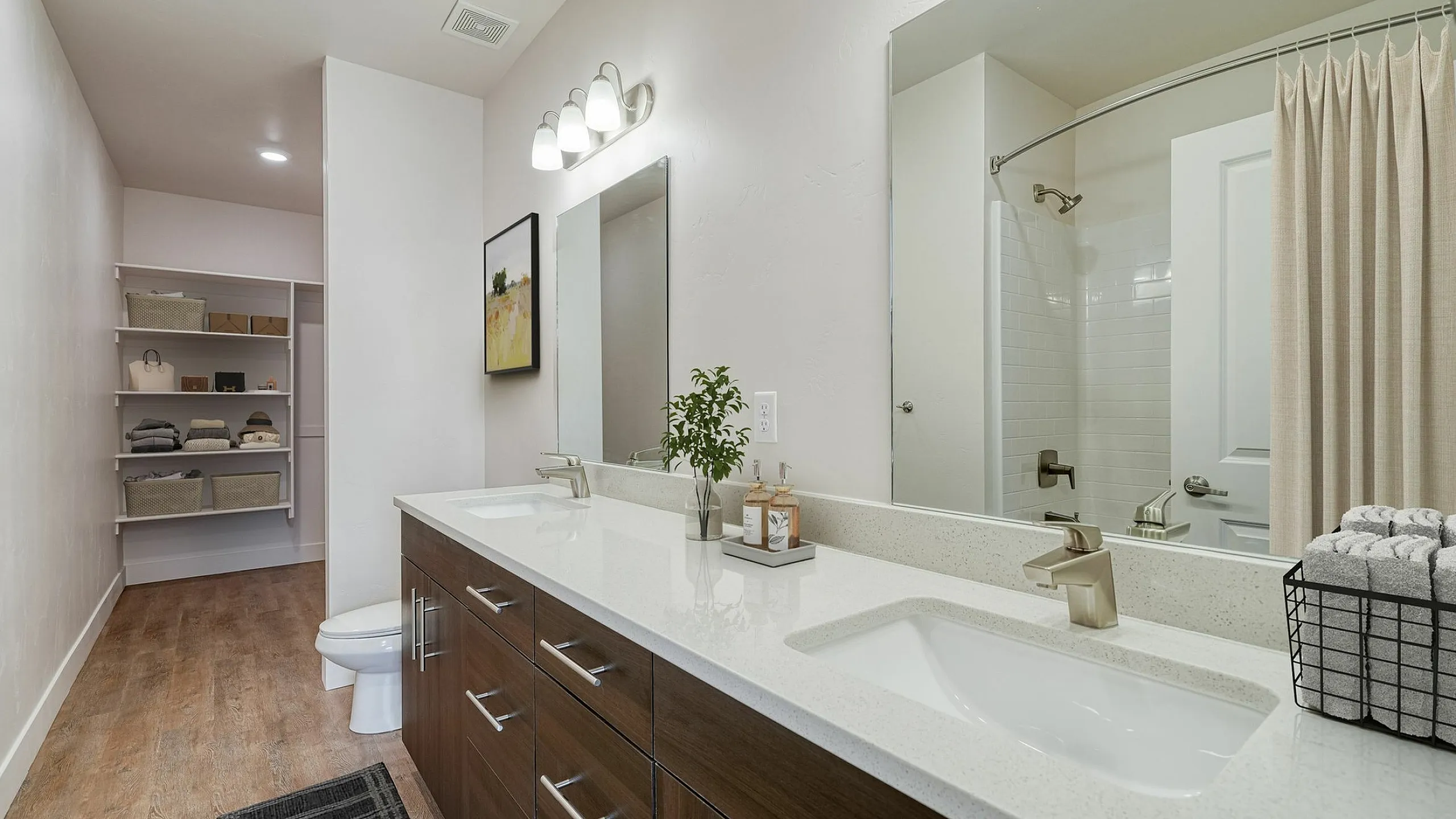 Elegant bathroom with double sinks and spacious countertop, featuring modern fixtures and open shelving for stylish storage.