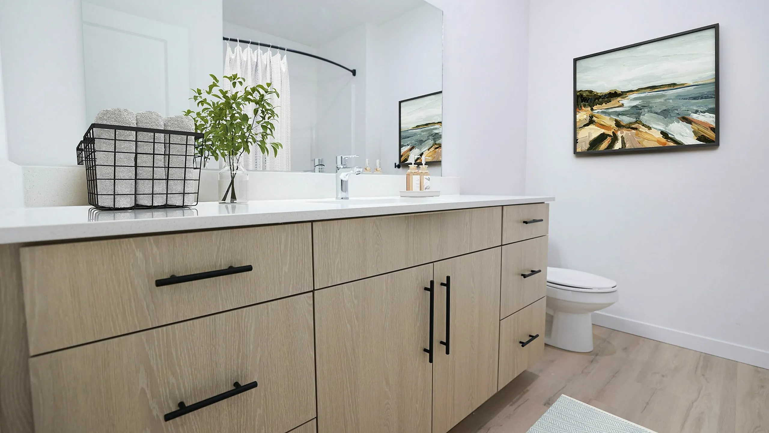 Elegant modern bathroom featuring sleek wooden cabinetry, large mirror, and minimalist decor with a vibrant wall painting.