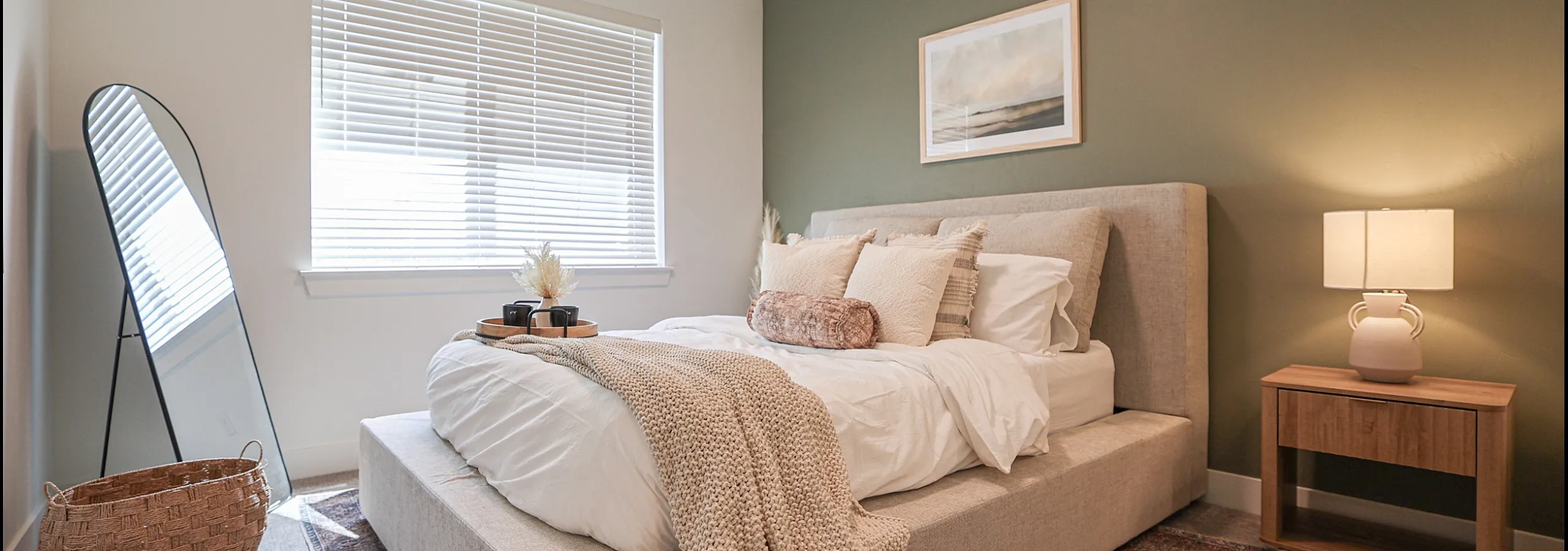Charming bedroom featuring a cozy bed with plush pillows, elegant decor, and a stylish full-length mirror accentuating the tranquil ambiance.