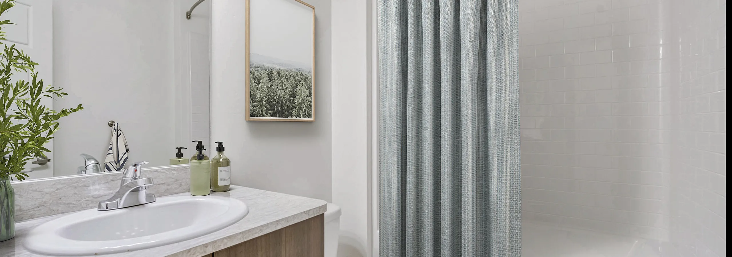 Modern bathroom with sleek white countertops, elegant wooden cabinetry, and a contemporary shower curtain, accented by charming greenery.