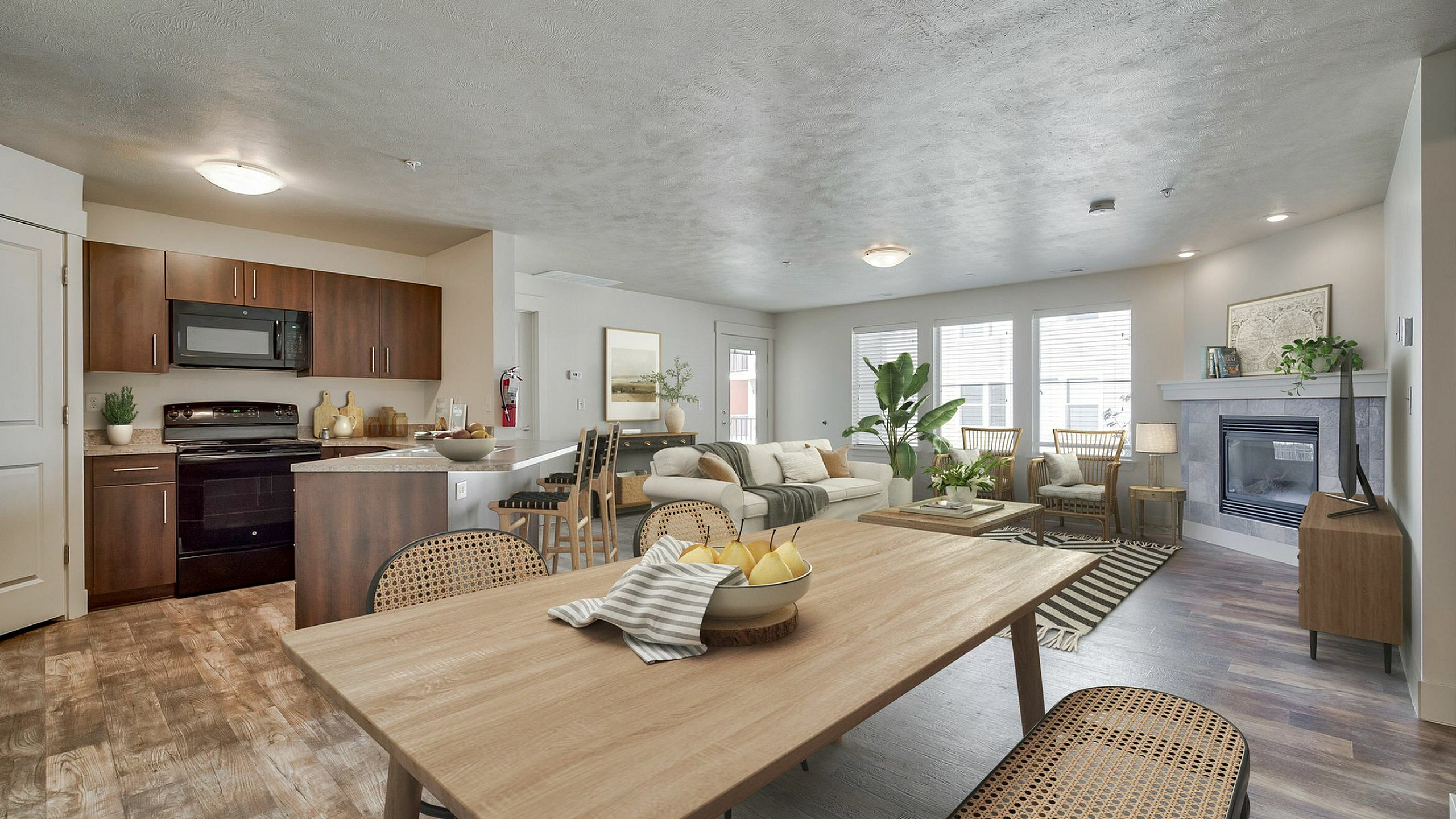 Bright, modern open-concept living area featuring a stylish kitchen, dining space, and cozy living room with a fireplace, all accentuated by abundant natural light.