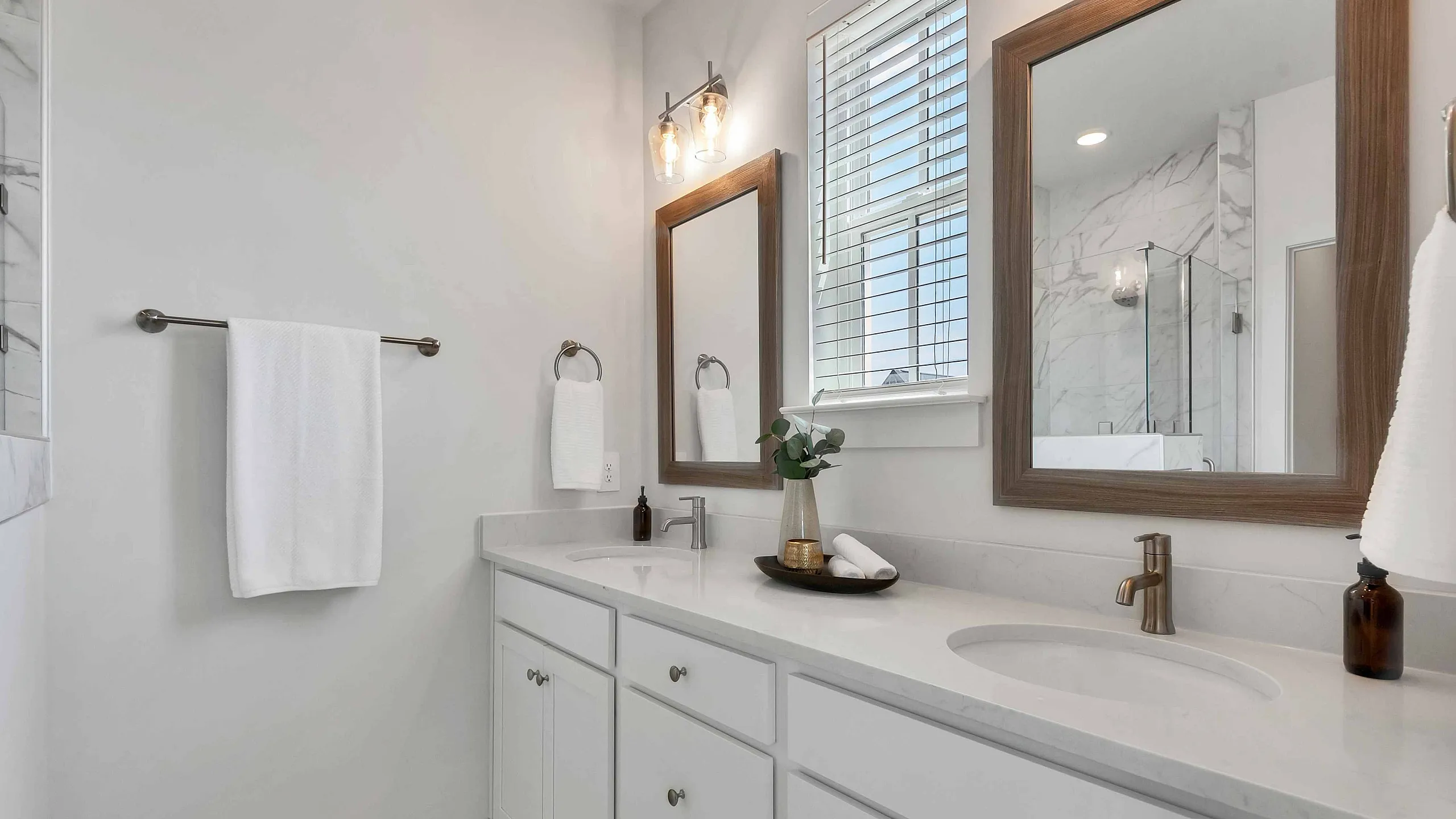 Elegant modern bathroom with dual sinks, sleek marble countertops, and stylish mirrors, offering a serene and luxurious atmosphere.