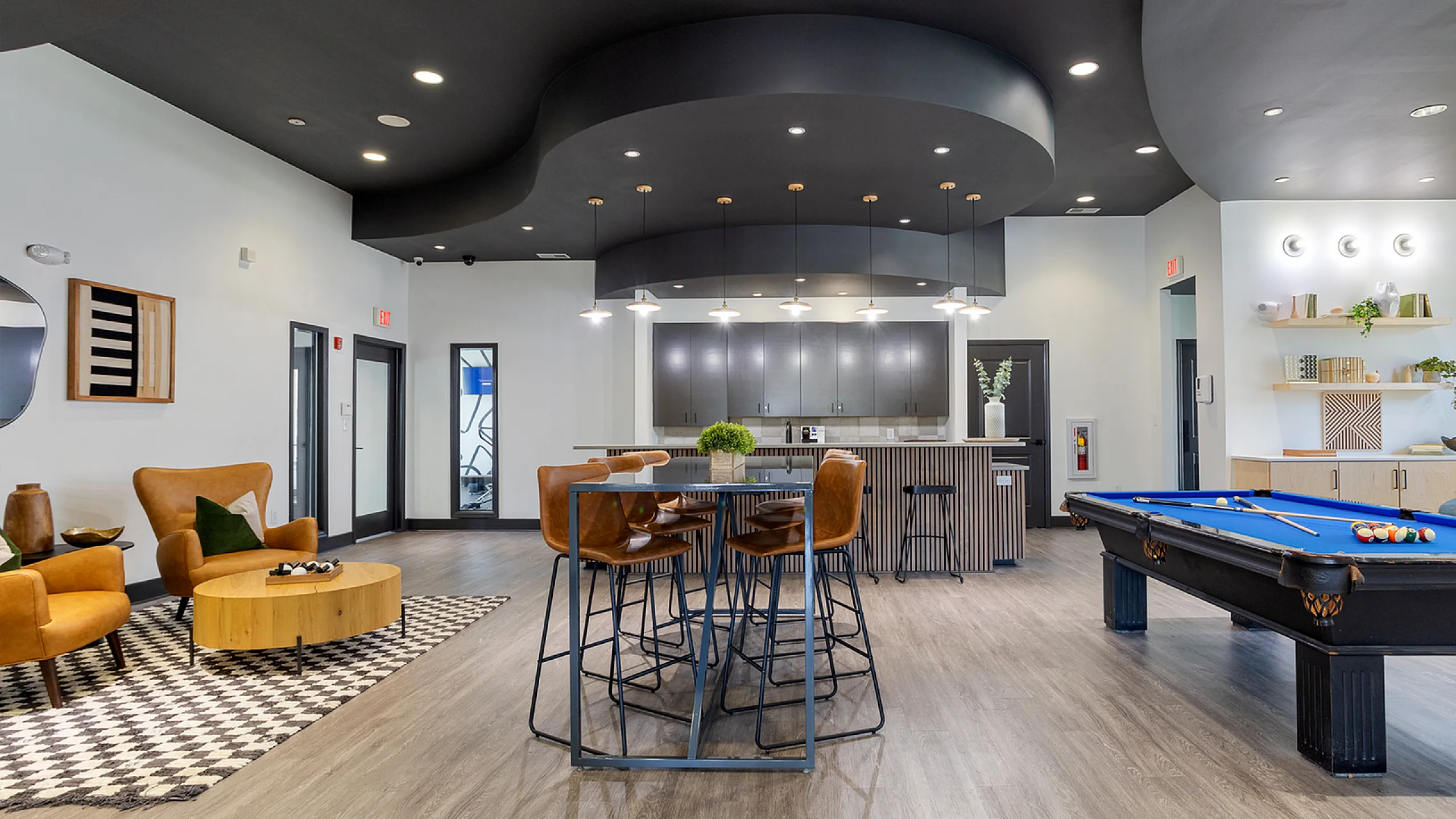 Modern communal space with sleek kitchen, cozy seating, stylish decor, and inviting pool table for entertainment.