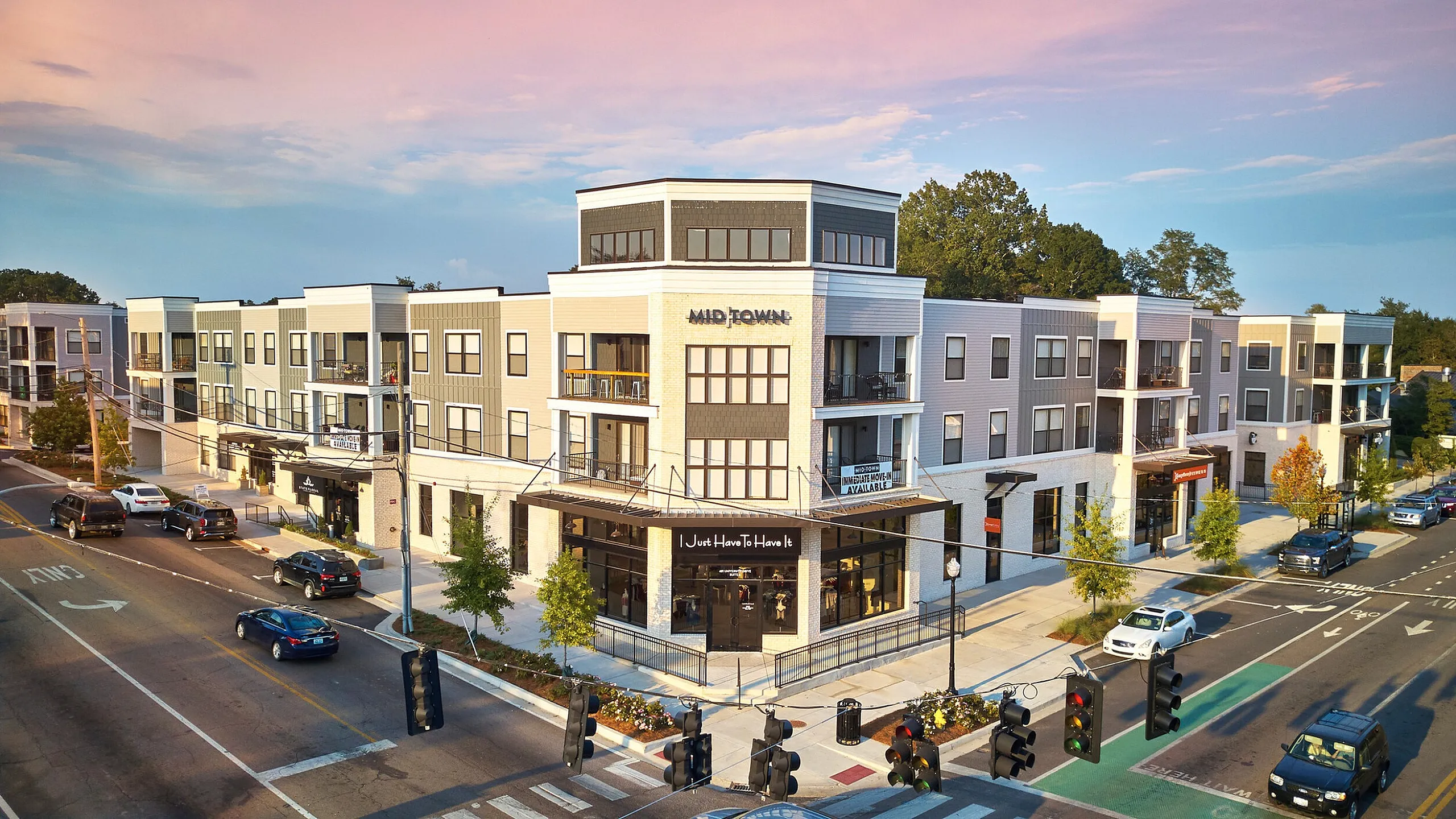 Modern three-story apartment building with stylish balconies and retail shops at street level, set against a vibrant urban backdrop with a pastel sky.