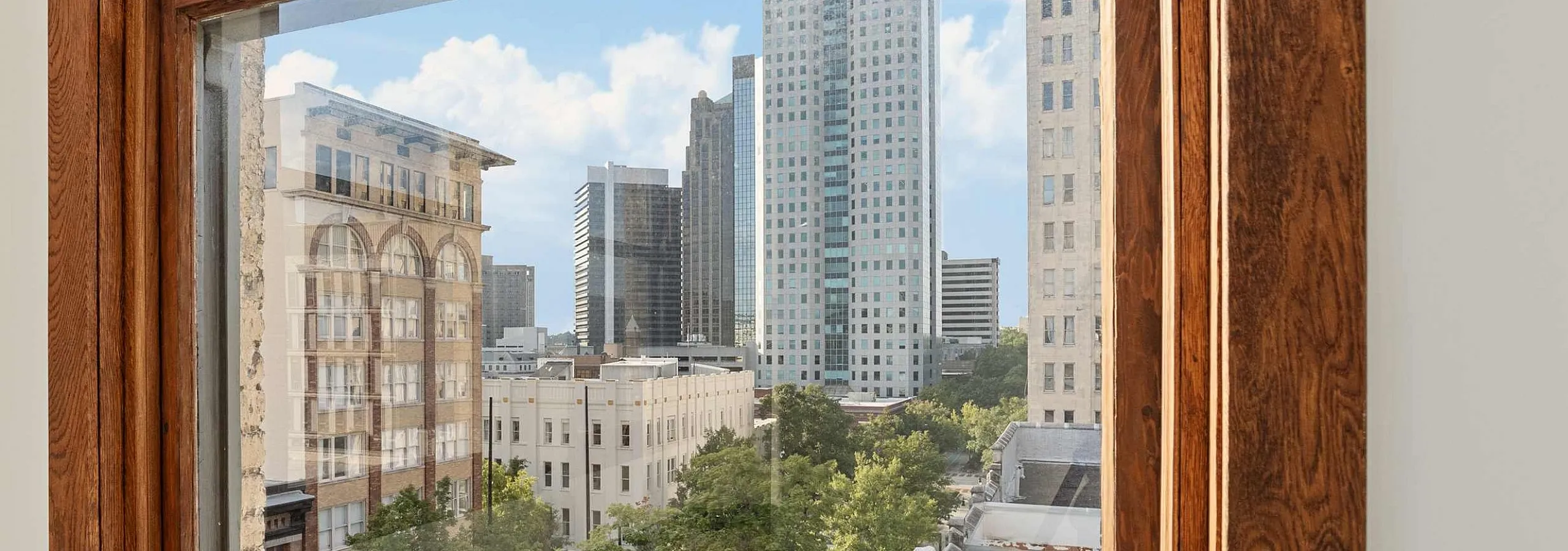 Charming apartment view showcasing vibrant city skyline through classic wooden-framed window.